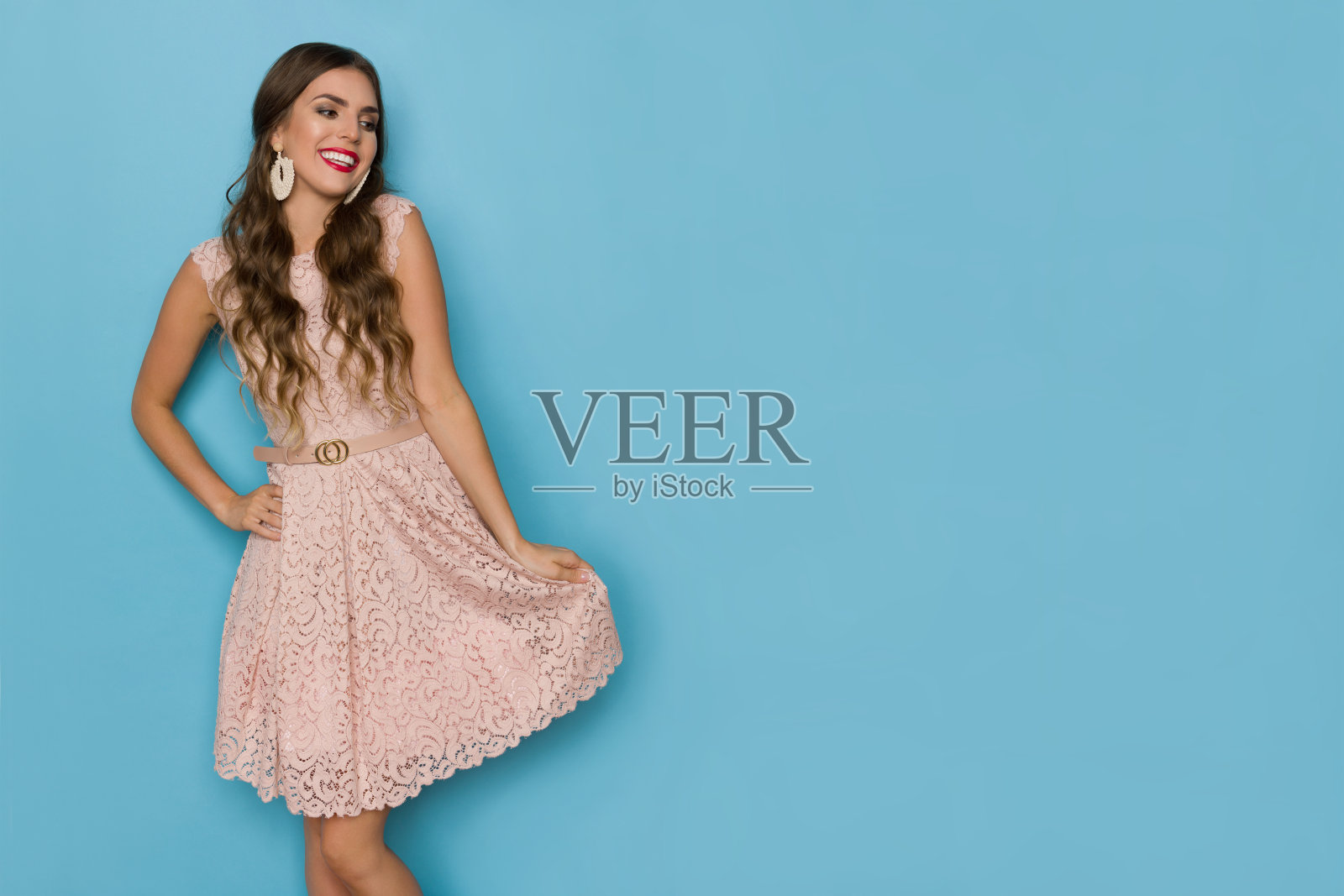 快乐美丽的女人在米色蕾丝迷你裙是看一边。照片摄影图片