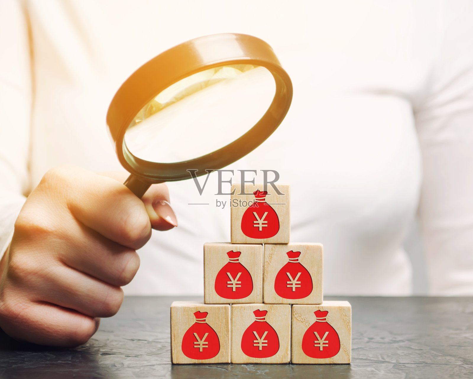 女商人用放大镜观察带有金钱的木块。商业概念:利润、财务和预算管理。计划、资金分配、资本、分析、投资照片摄影图片