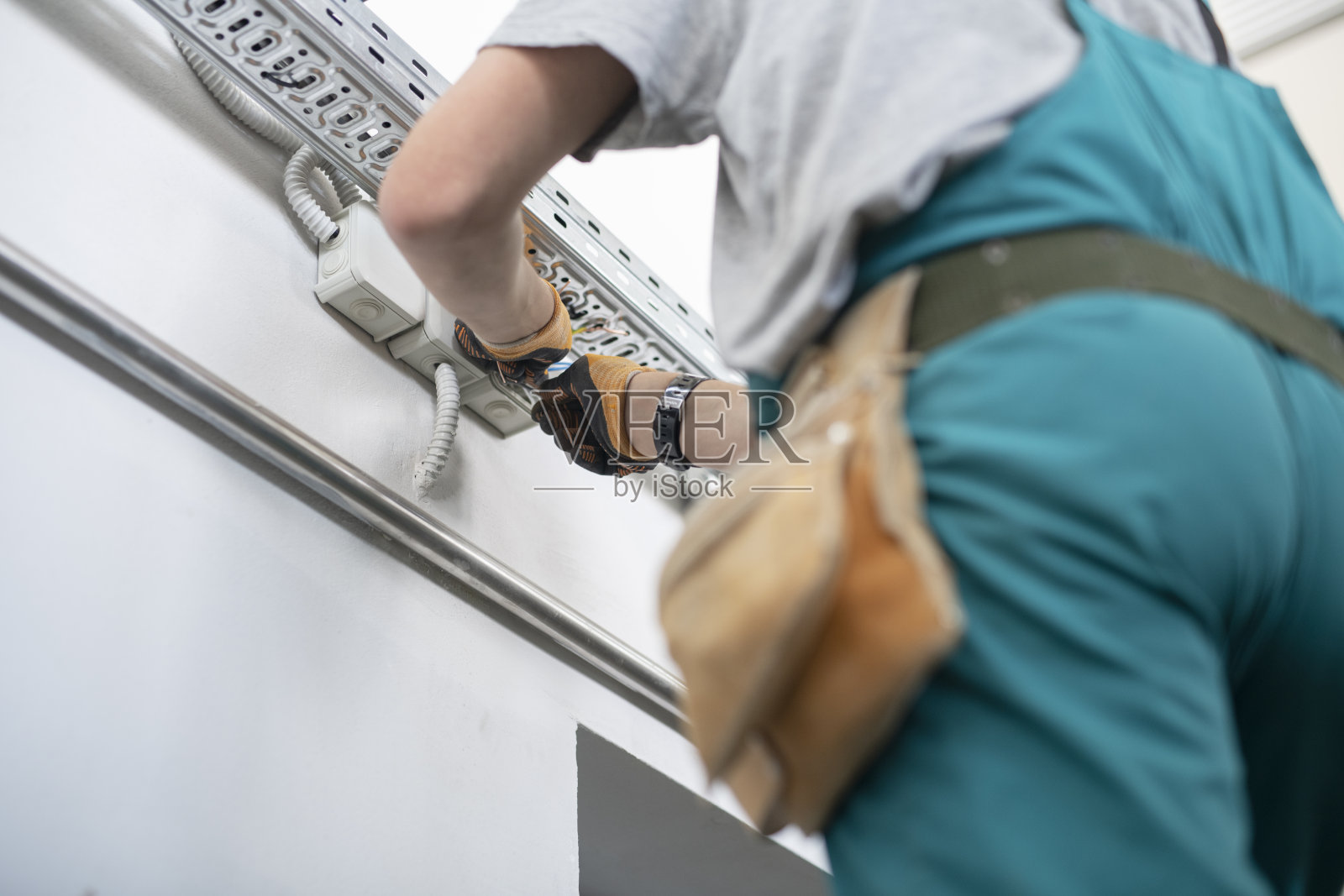 不认识的人在室内做电工线。照片摄影图片