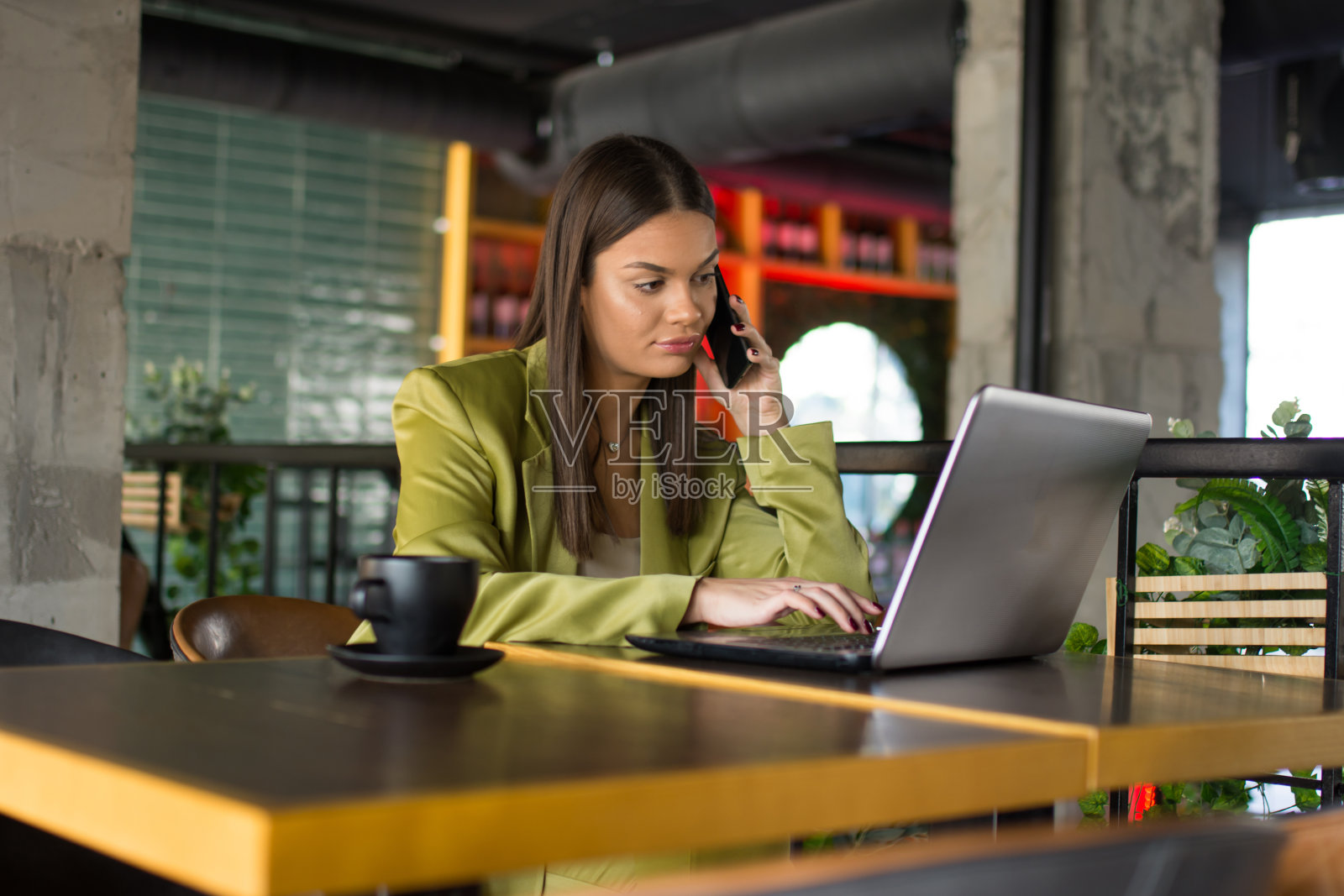 年轻女商人在咖啡馆的桌旁使用笔记本电脑和手机照片摄影图片