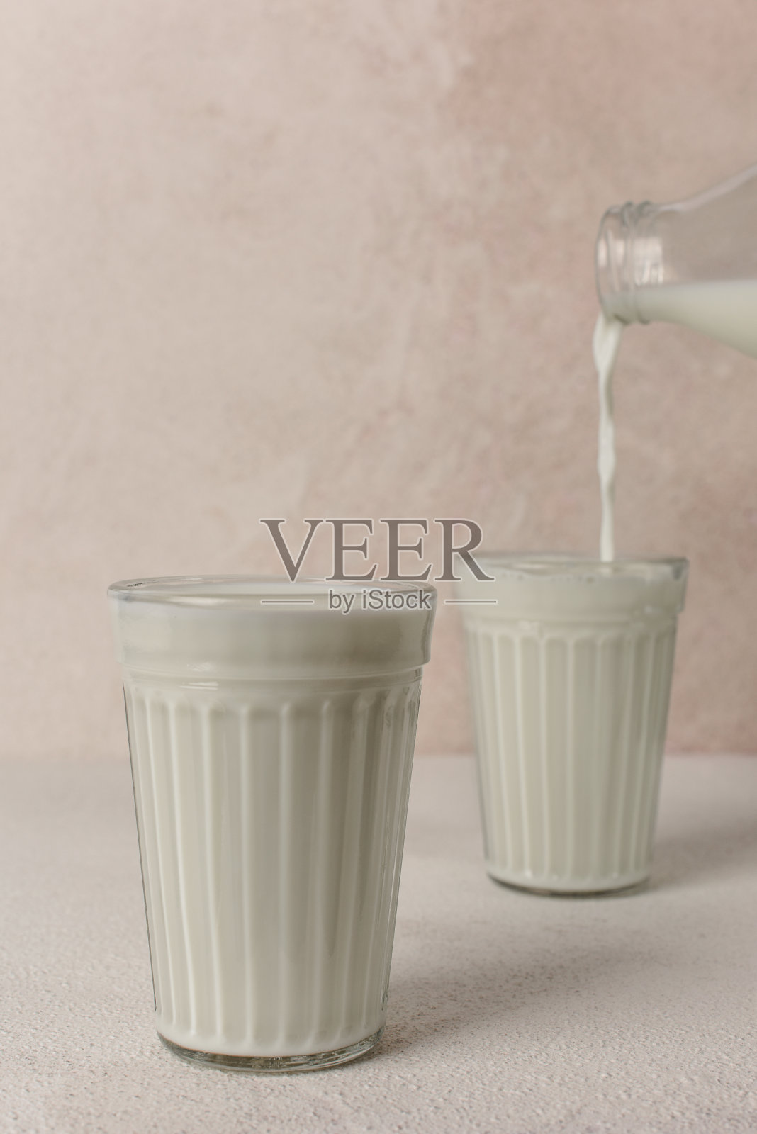 两杯牛奶。牛奶从瓶子倒进玻璃杯里。副本的空间。照片摄影图片