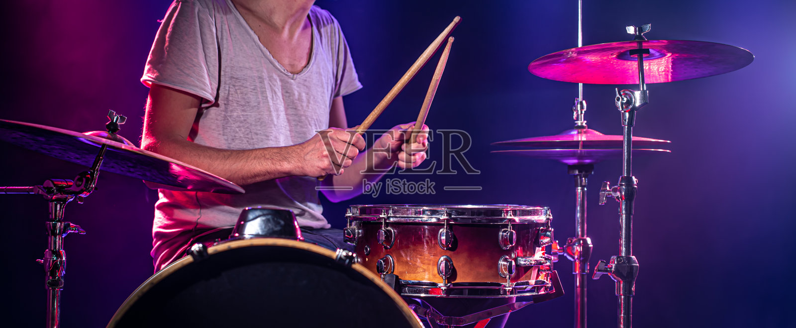 鼓手打鼓。美丽的蓝色和红色背景,与光线。美丽的特效烟雾和灯光。演奏乐器的过程特写照片。照片摄影图片