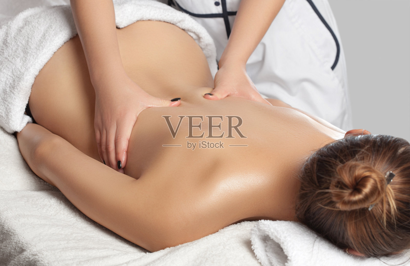 按摩师在水疗中心为年轻美丽的女子进行放松的颈、肩、背部按摩。美容和按摩概念照片摄影图片