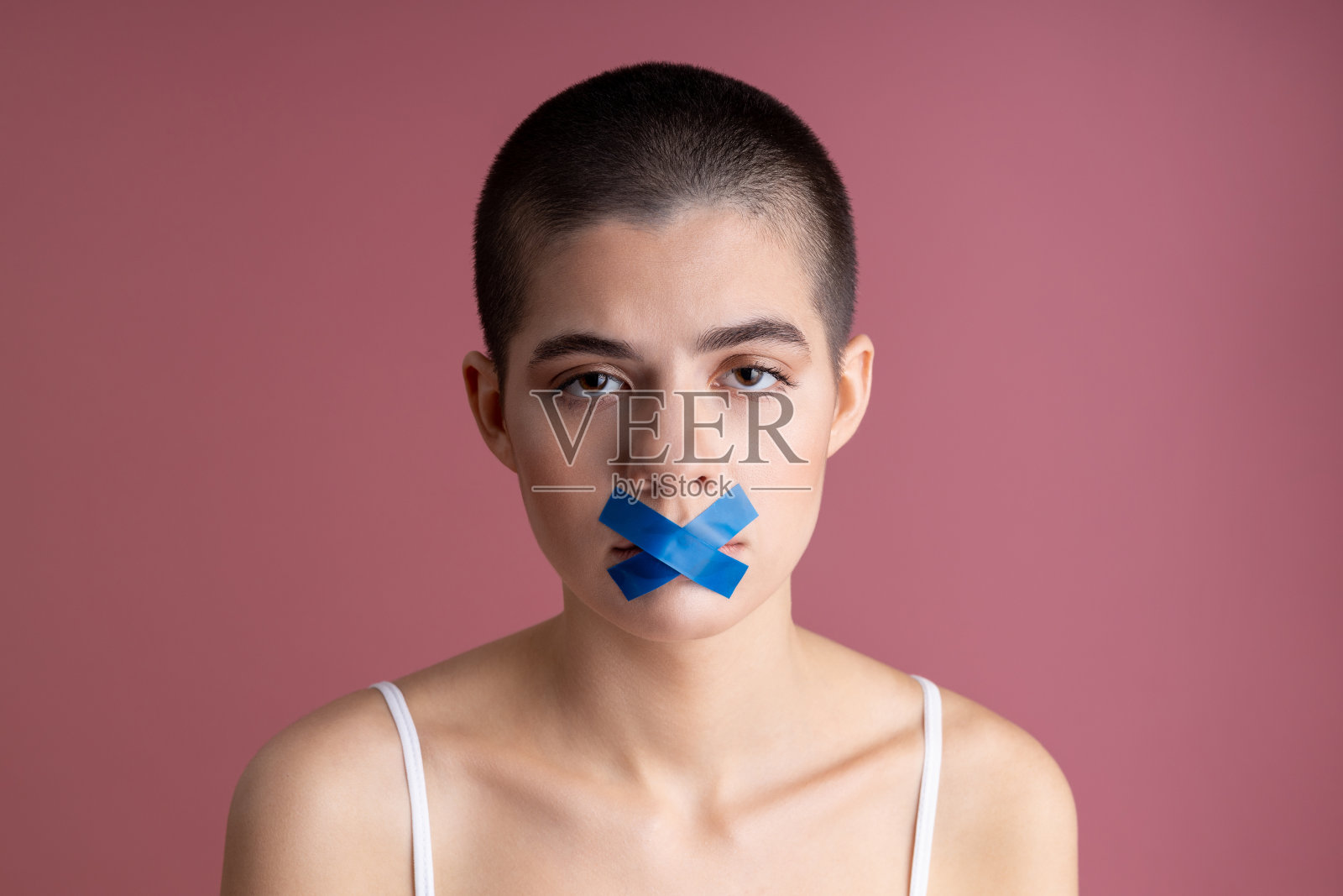 嘴上贴着蓝色胶带的悲伤女人照片摄影图片