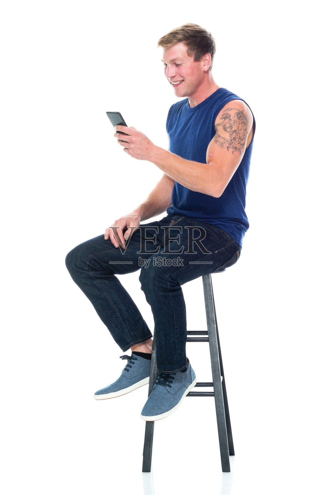 白人男性无袖坐着穿背心和使用智能手机照片摄影图片
