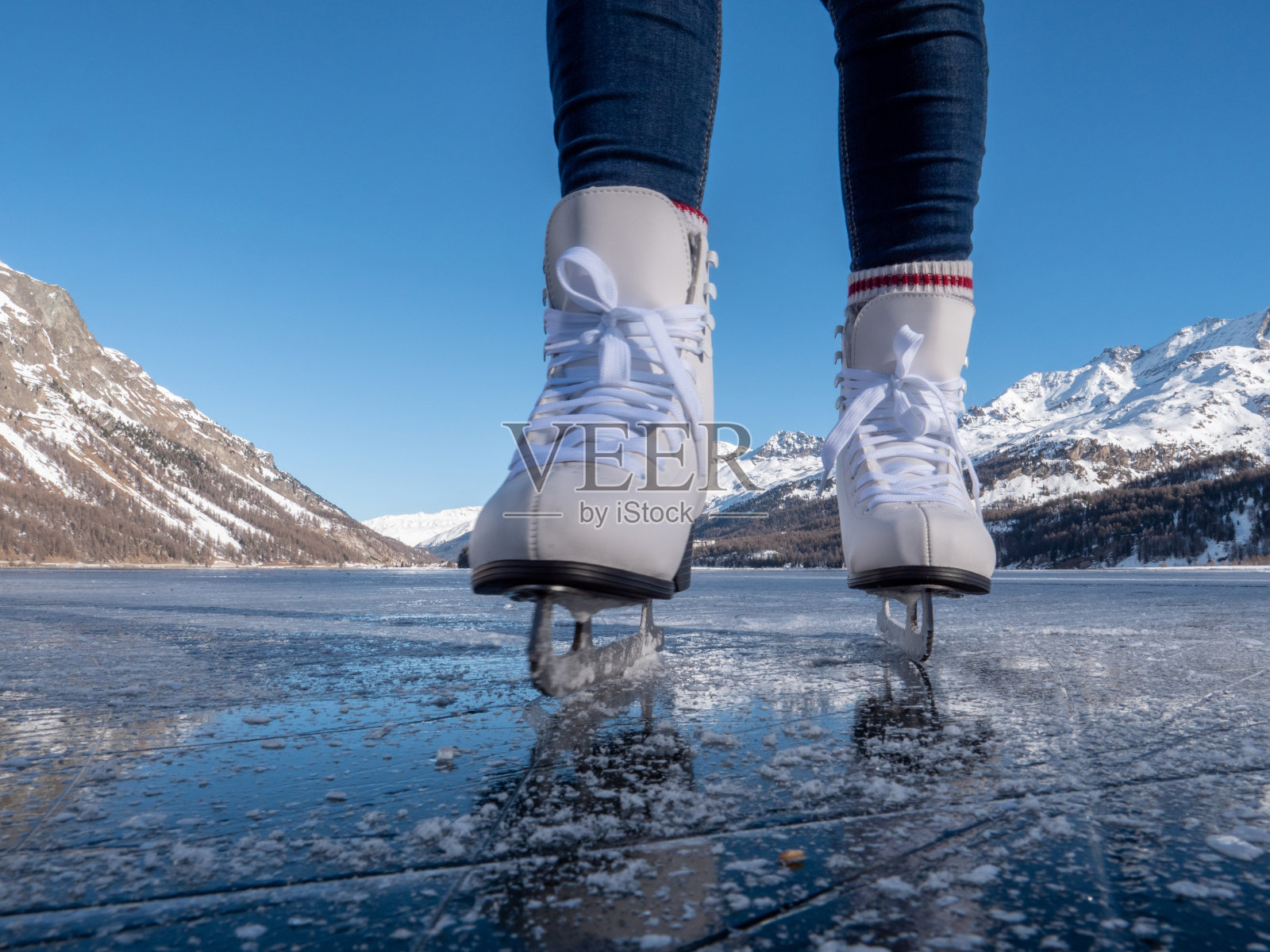 日落时分,在结冰的湖面上穿着溜冰鞋的双脚照片摄影图片