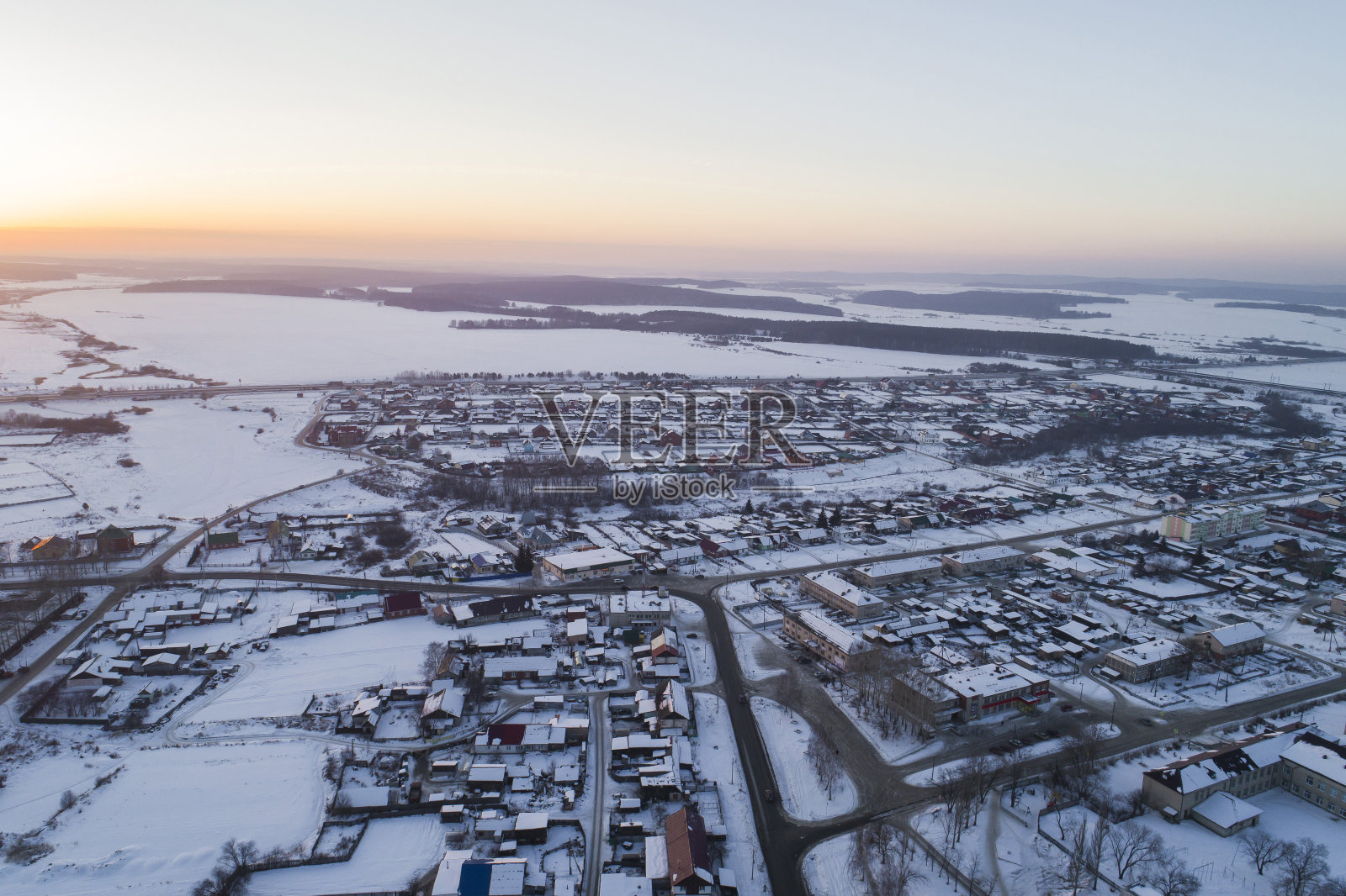 鸟瞰图Oktyabrski村庄与道路和车里雅宾斯克道路在地平线上。俄罗斯。冬天,傍晚,日落照片摄影图片
