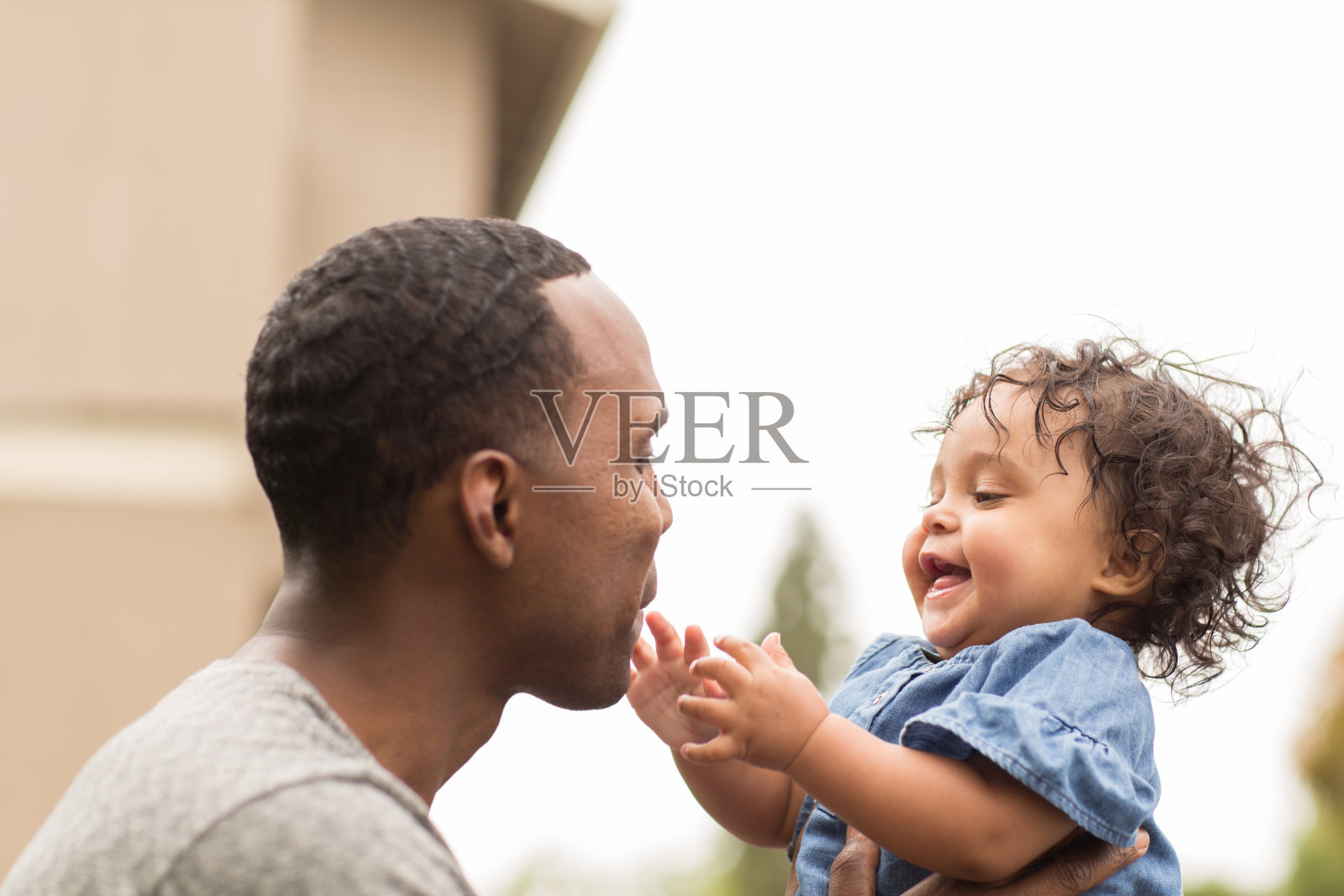 父亲抱着他的小女孩。混血家庭。照片摄影图片