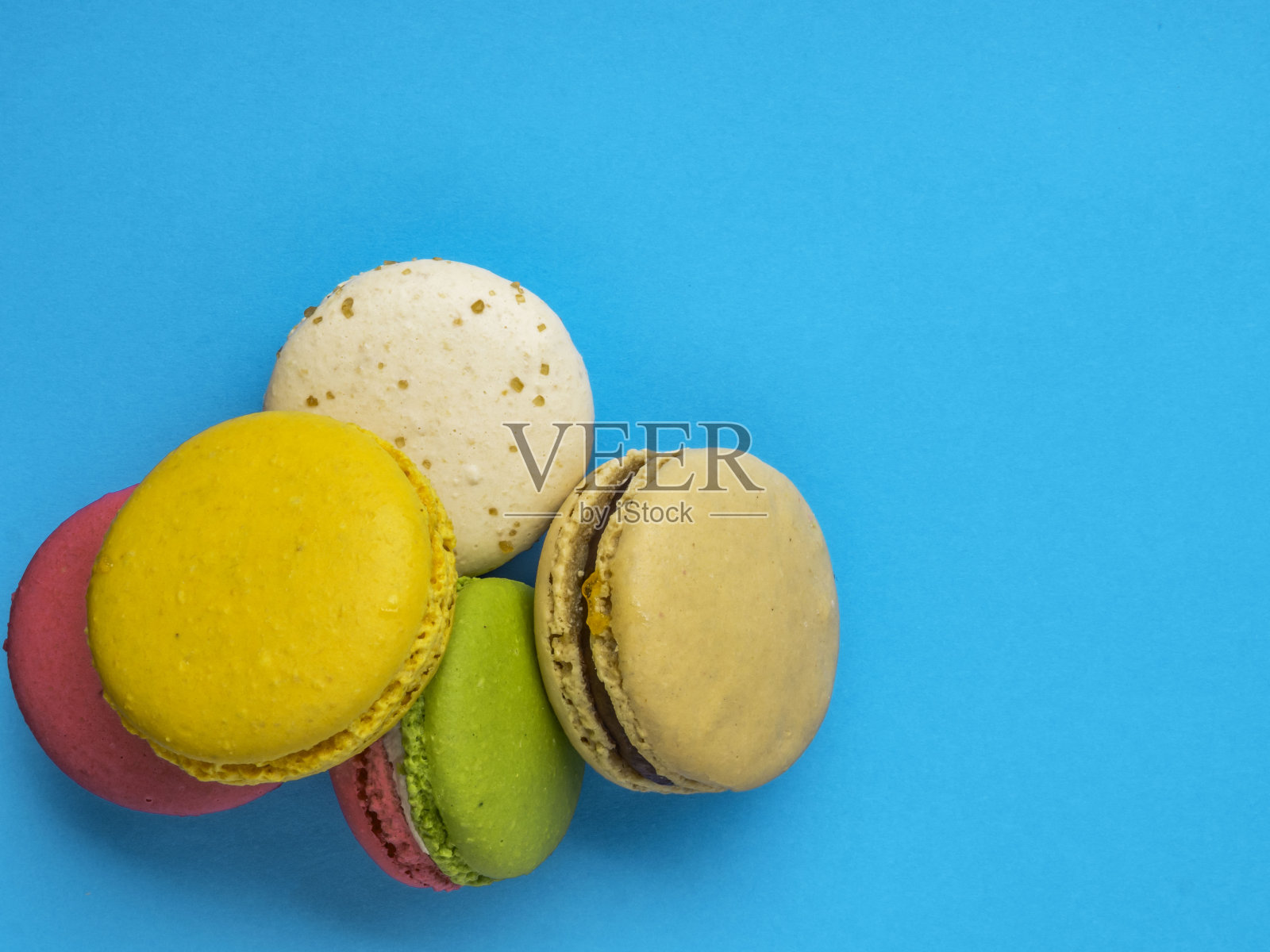 蓝色背景上五颜六色美味的法式马卡龙。前视图。照片摄影图片