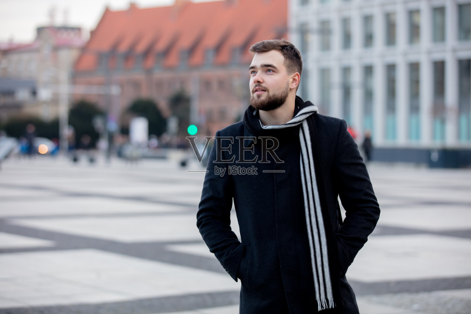 在城市街道上围着围巾,穿着外套的英俊男人照片摄影图片