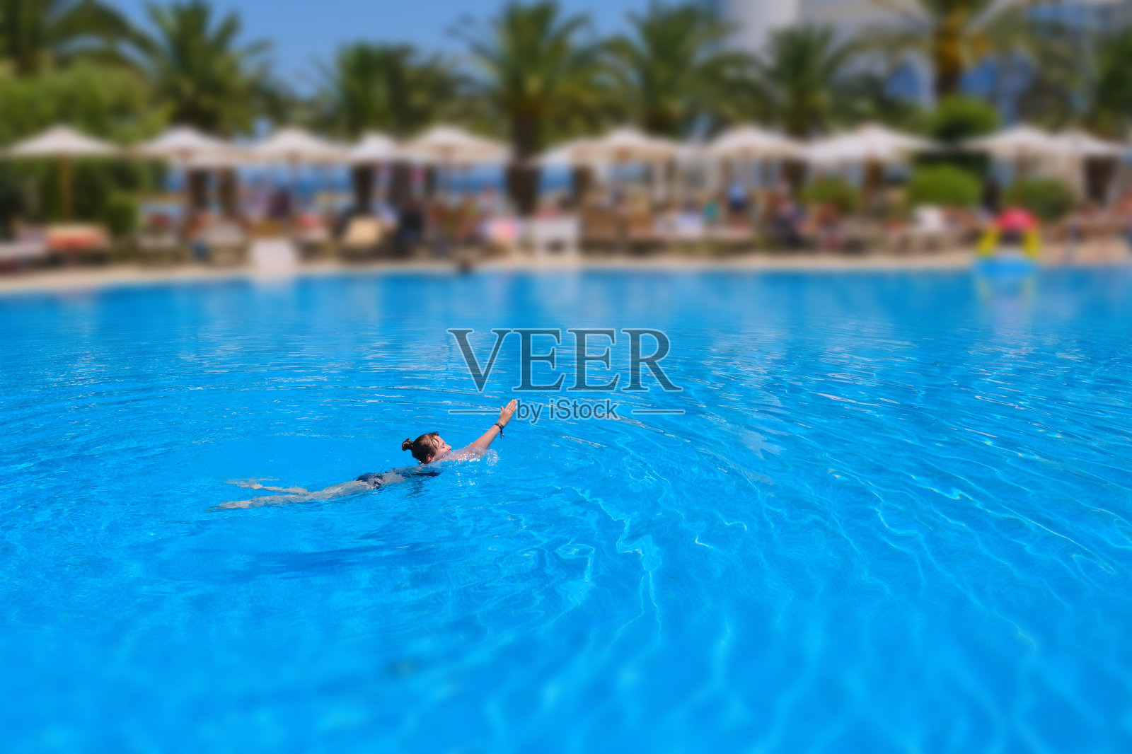 在酒店游泳池里游泳的女孩,移轴效果照片摄影图片