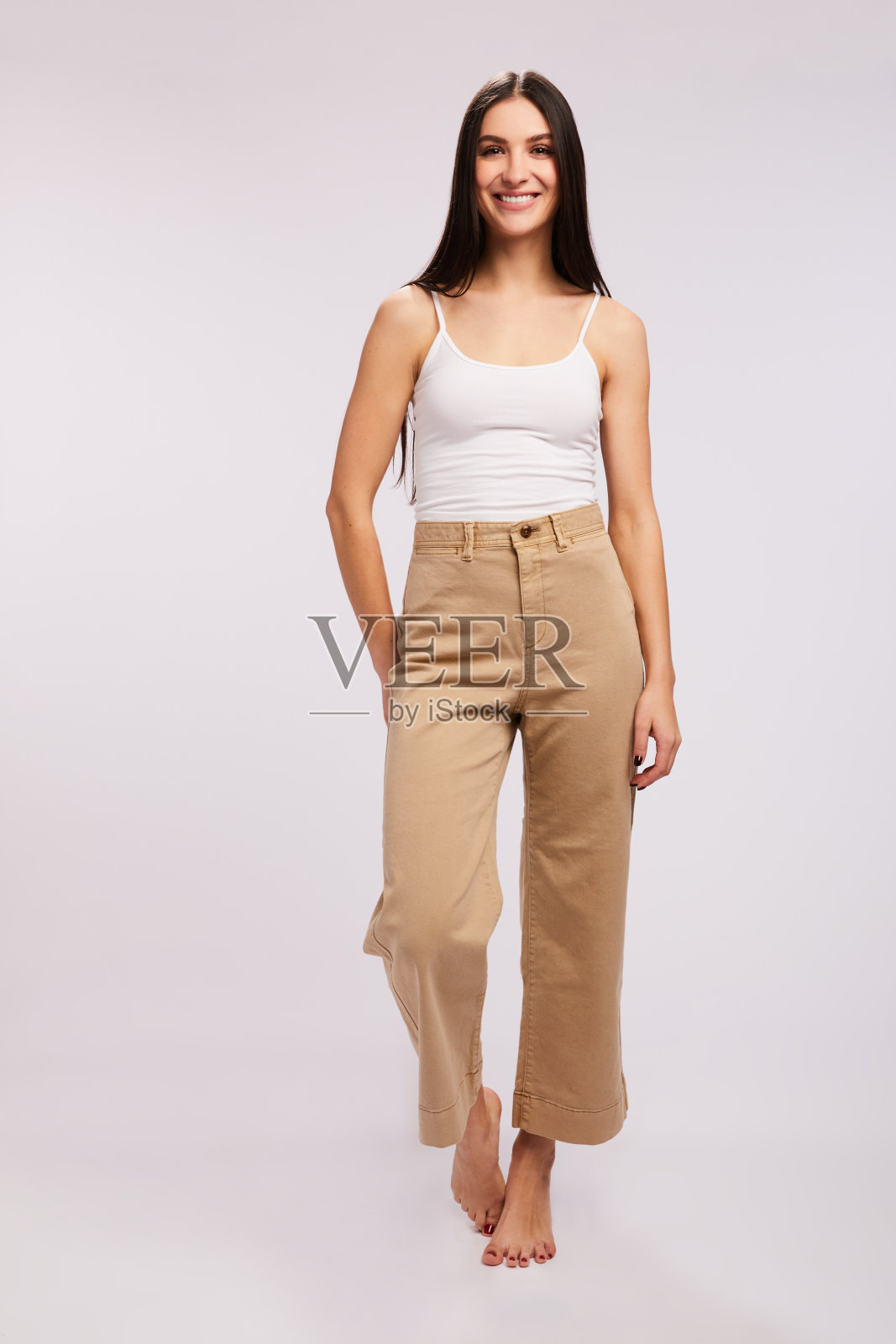 穿得很随便的褐发姑娘在灰色的背景下微笑着照片摄影图片