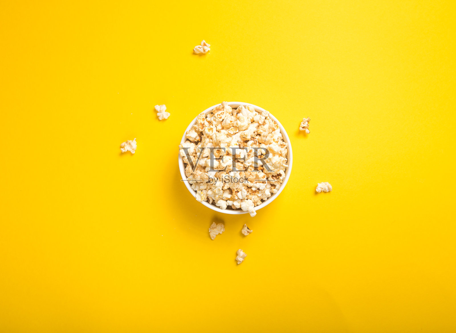 从上面黄色背景上看爆米花。平的碗。俯视图照片摄影图片