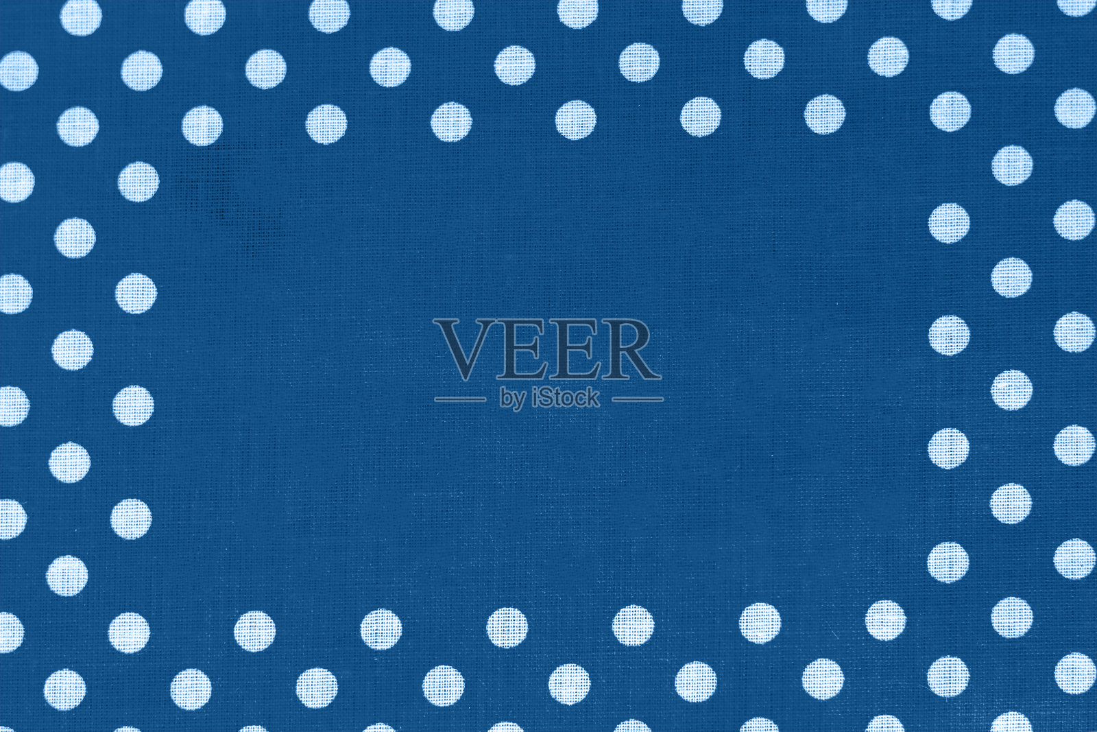 波尔卡点在经典的蓝色帆布棉纹理与复制空间在中间。带有白色圆圈的蓝色织物。色彩鲜艳的棉背景照片摄影图片