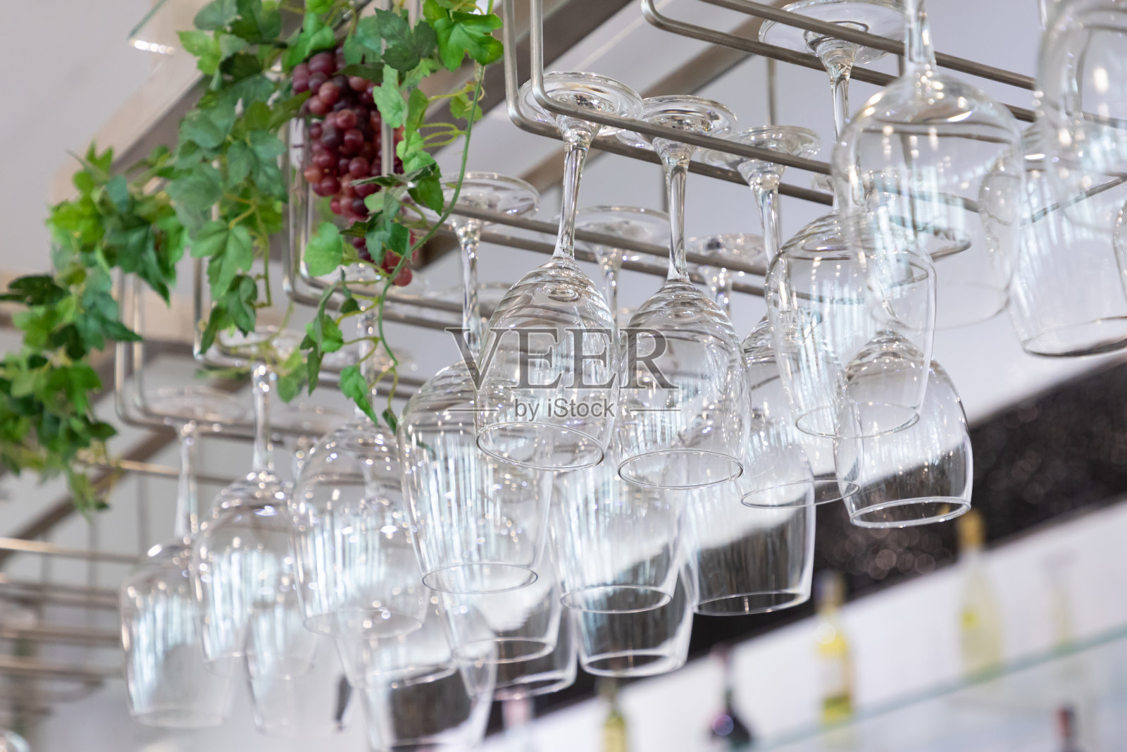 酒杯挂在酒吧的不锈钢架上。照片摄影图片