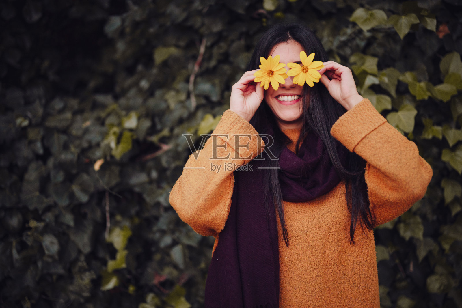 微笑的女人在田野里玩弄一朵黄花照片摄影图片