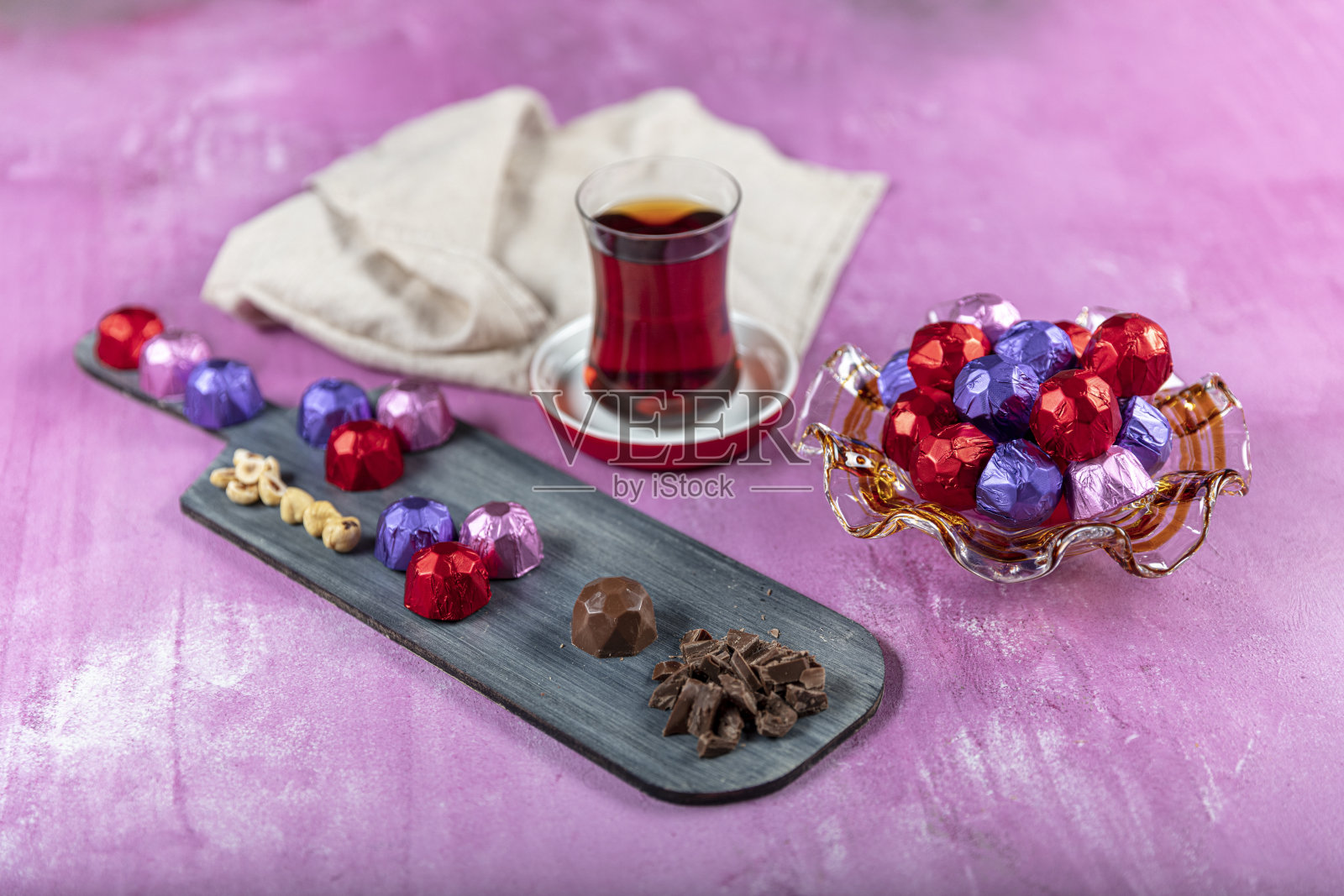 榛子巧克力上覆盖着红色、紫色和粉红色的箔纸,以木制里拉为背景。开斋节(斋月盛宴)的概念。照片摄影图片