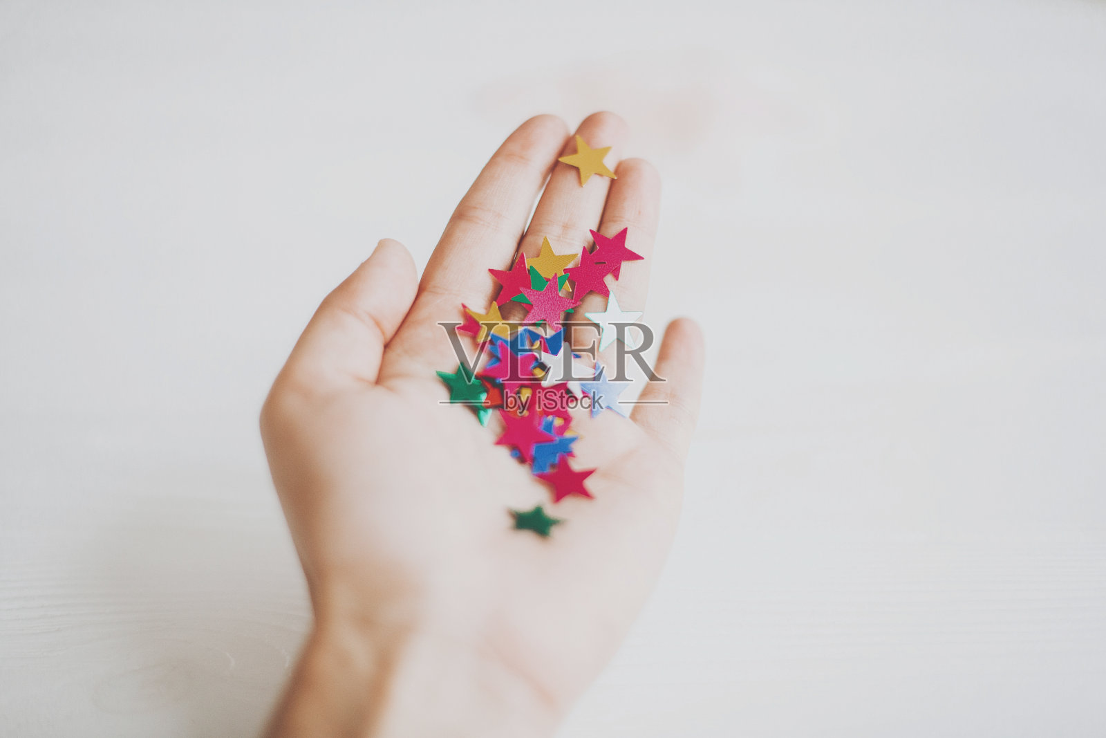 手拿彩色星星纸屑或闪光粉,白色背景照片摄影图片