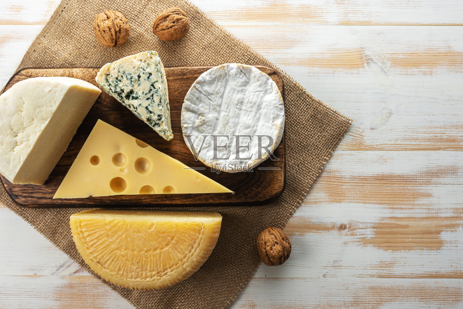 白色的木桌上放着各式各样的奶酪。奶酪的背景。照片摄影图片
