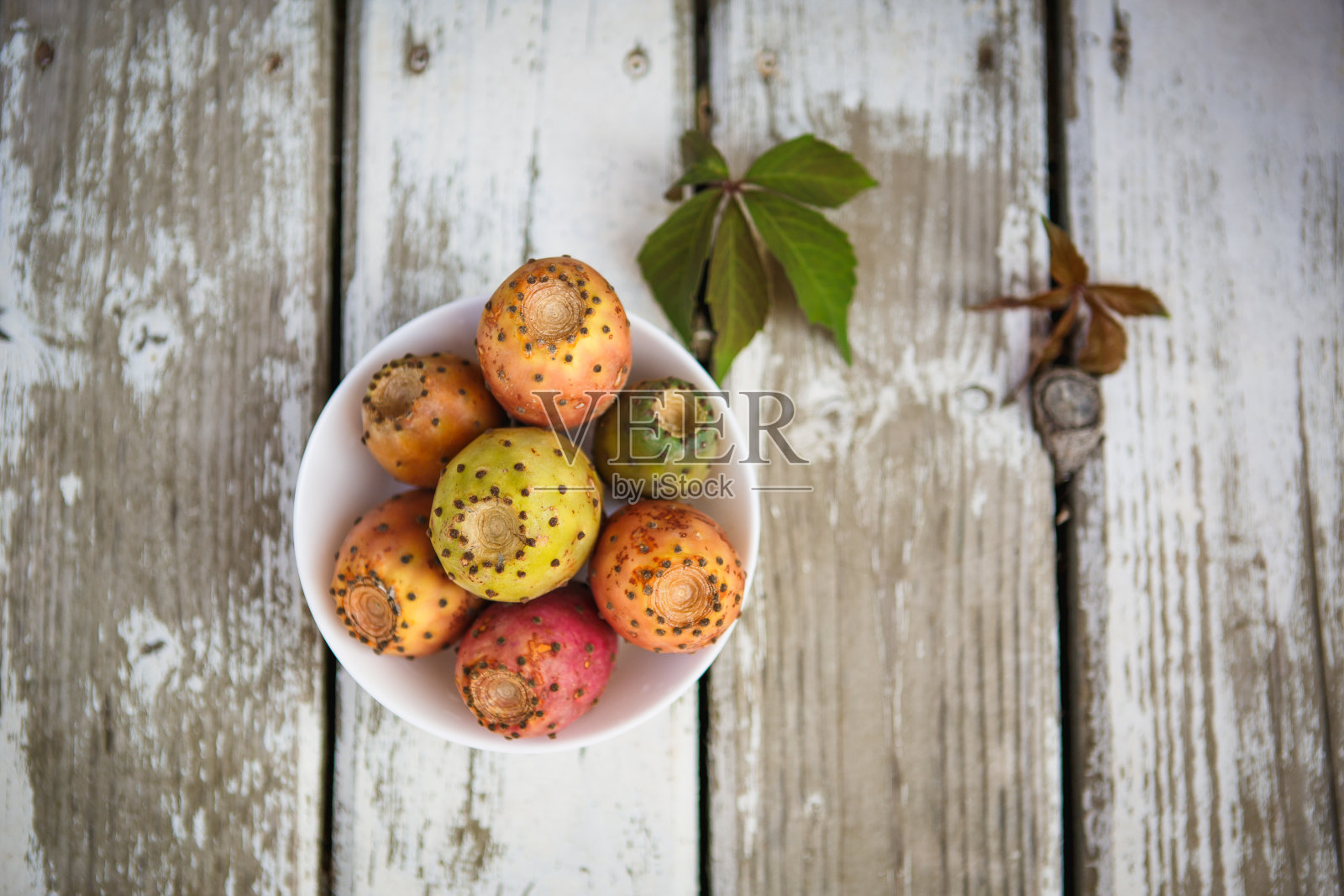 彩色多汁多刺的梨水果在一个白色的盘子和白色的木制背景。照片摄影图片