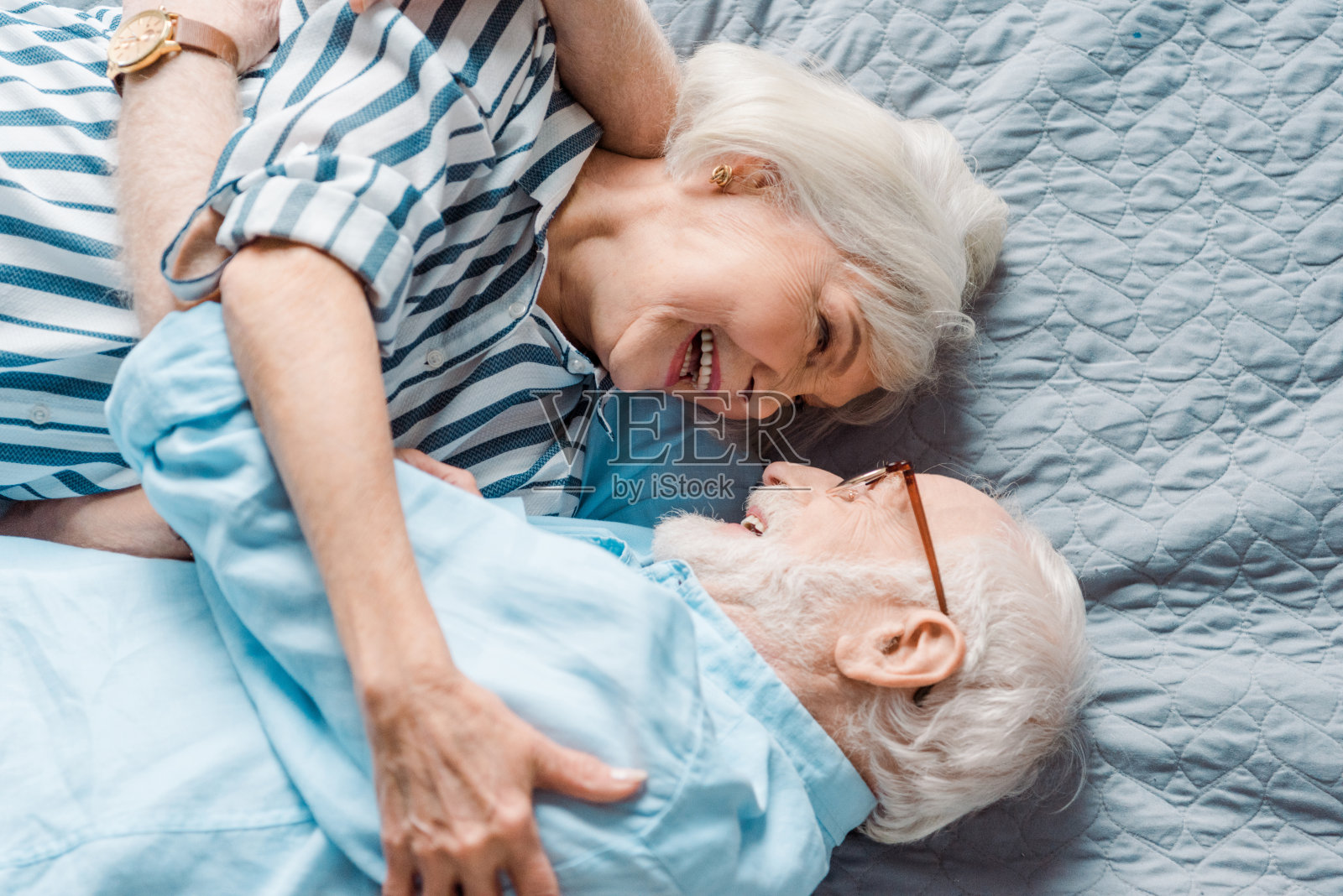 上面的老人夫妇在床上互相微笑照片摄影图片