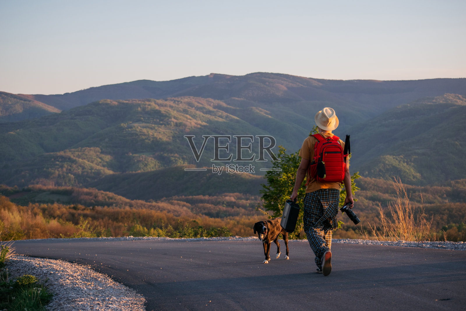 摄影师和他的狗在夕阳下散步照片摄影图片