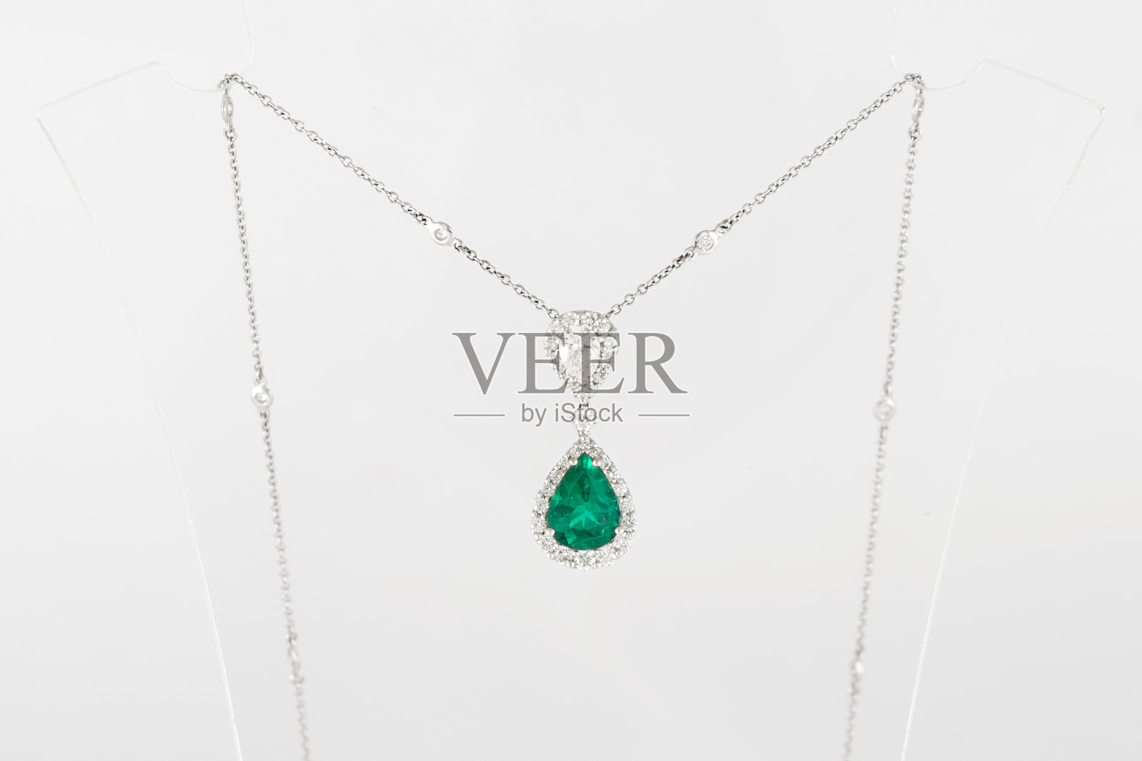 奢华的白色金色吊坠与绿色宝石和钻石站。照片摄影图片