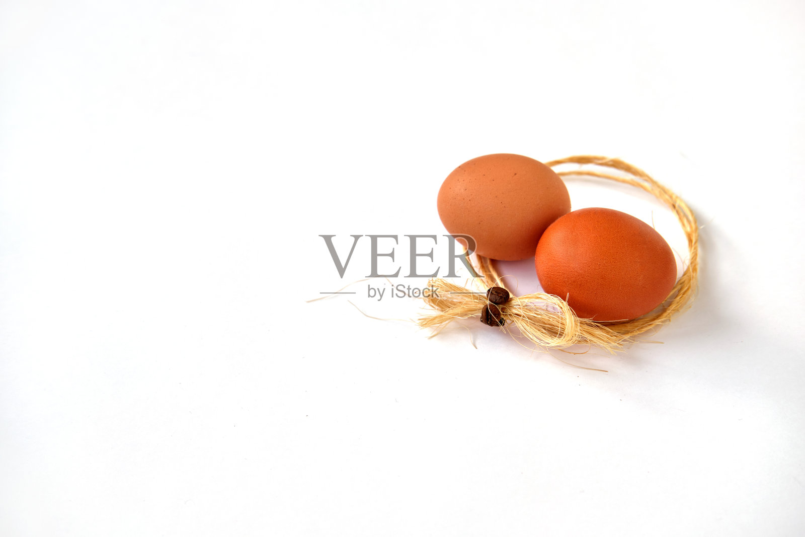 两个鸡蛋躺在一圈麻线在白色的背景照片摄影图片