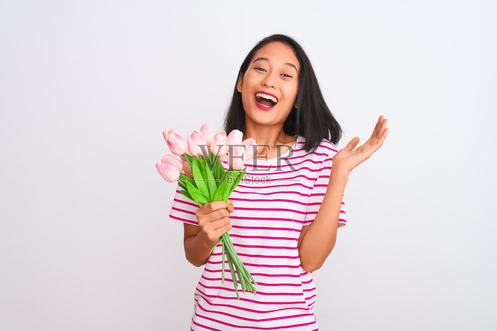 年轻的中国妇女拿着一束玫瑰站在孤立的白色背景非常高兴和兴奋,胜利者的表情庆祝胜利尖叫着大大的微笑和举起手照片摄影图片