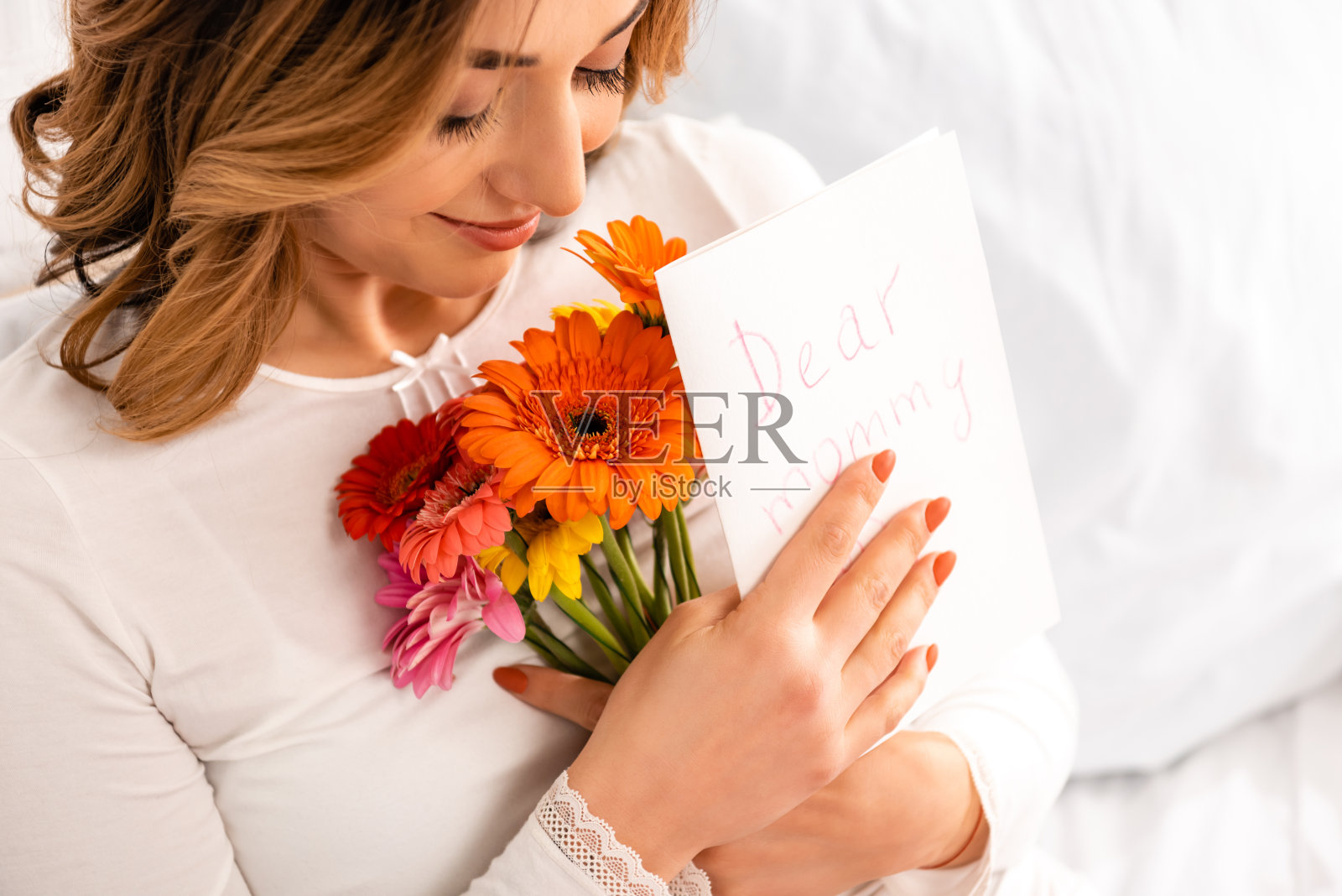 快乐的女人手捧非洲菊和母亲节贺卡微笑照片摄影图片