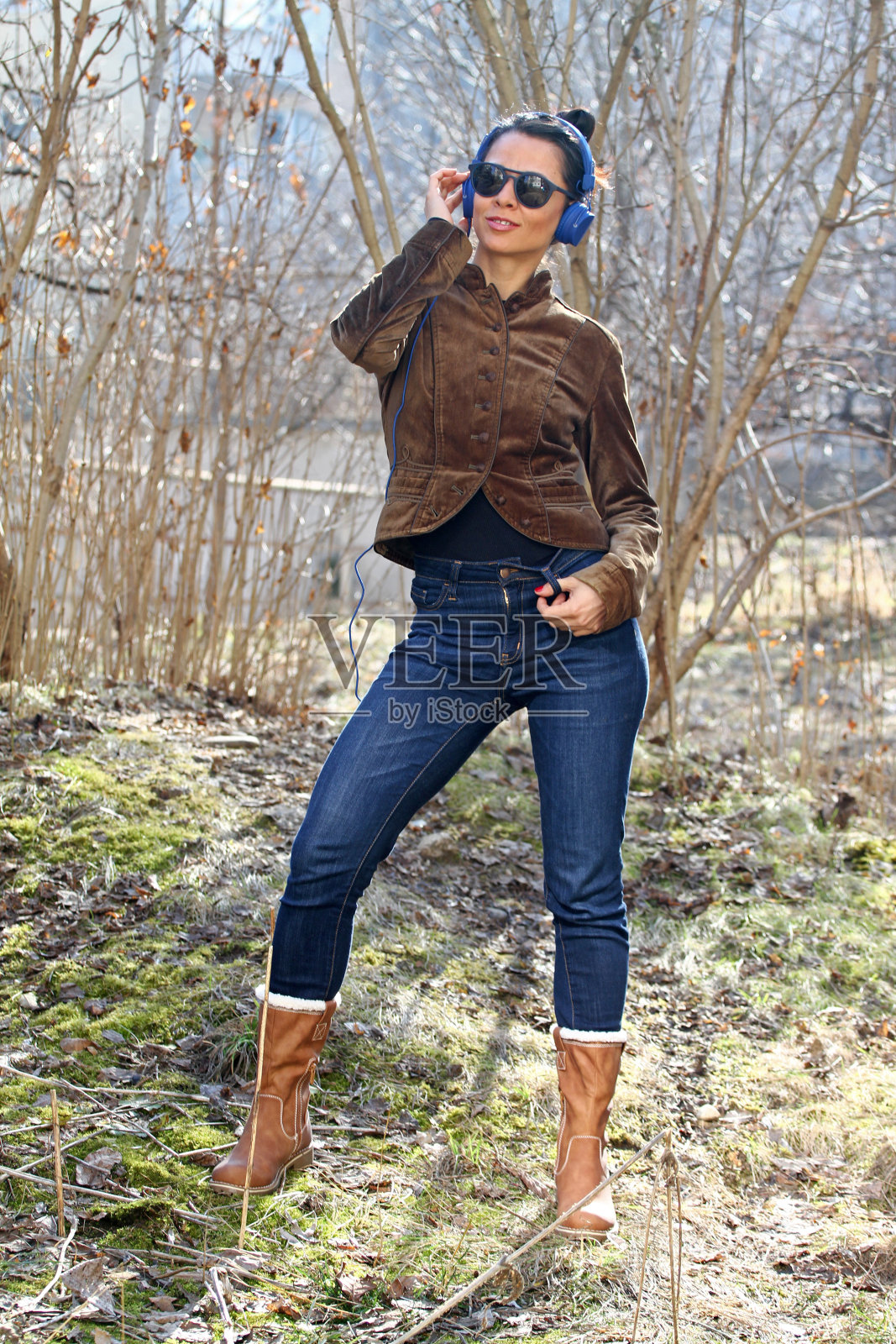 快乐的年轻女子戴着耳机听音乐,在公园里照片摄影图片