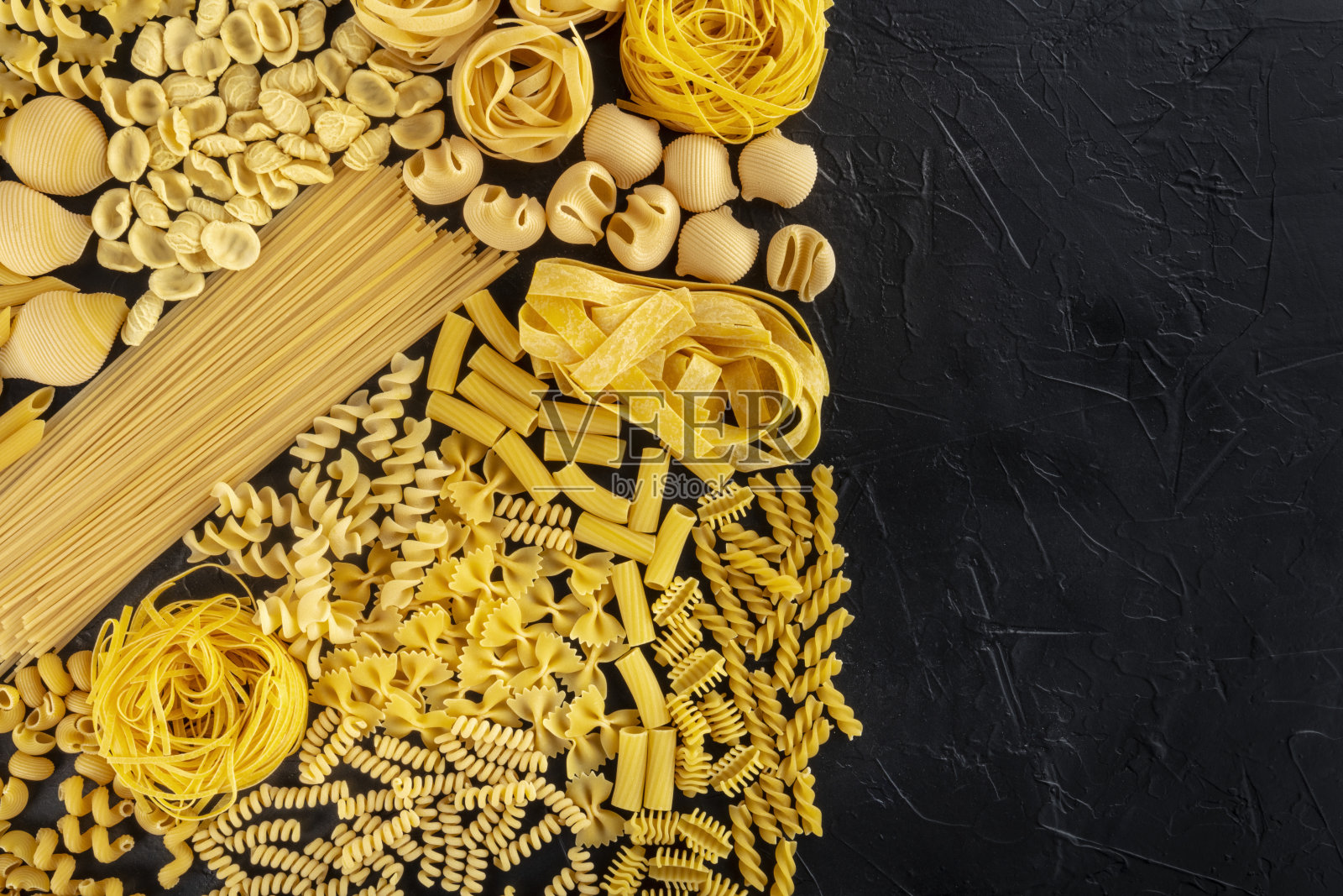 意大利面食设计模板与文本的地方,许多面食类型的分类,顶部拍摄的黑色背景照片摄影图片