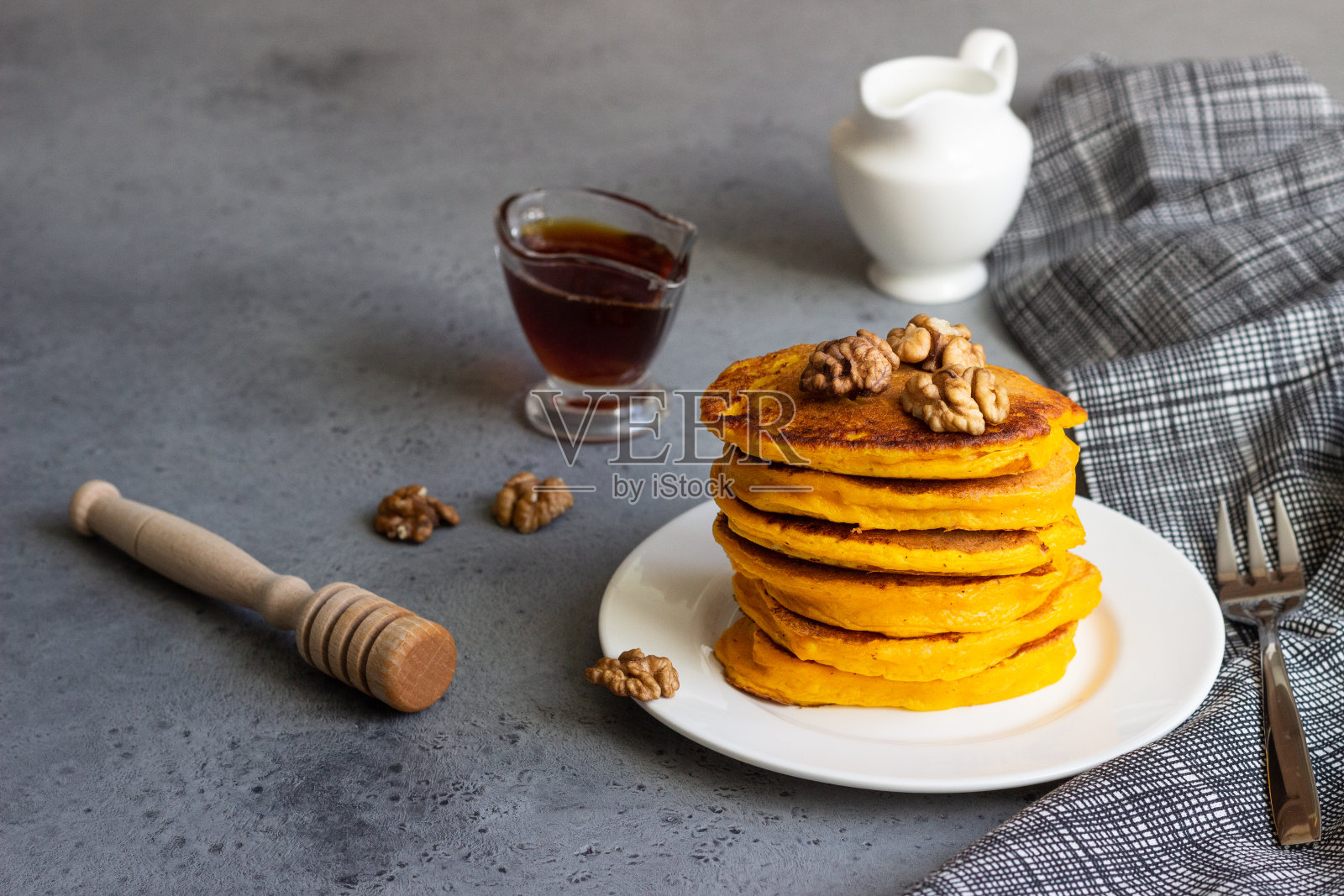 南瓜煎饼配枫糖浆或蜂蜜和核桃放在一个白色的盘子里。灰色的混凝土。副本的空间。健康的早餐。秋天的食物。照片摄影图片