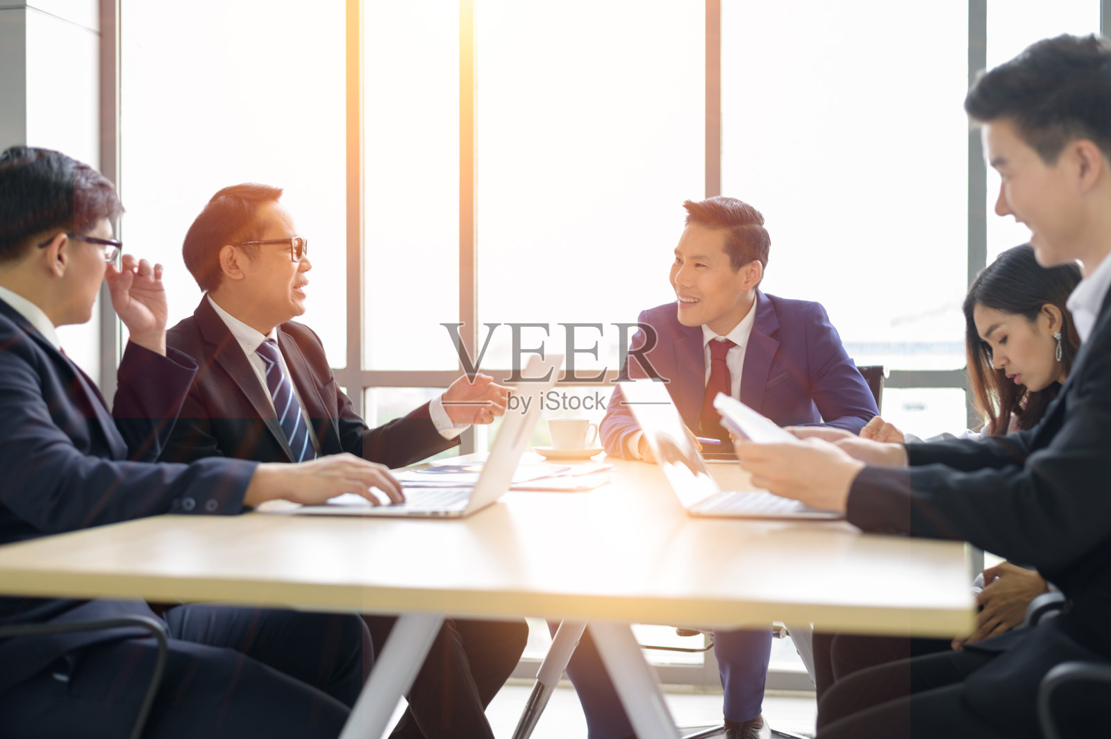 在办公室会议期间,亚洲商人在会议室交谈照片摄影图片