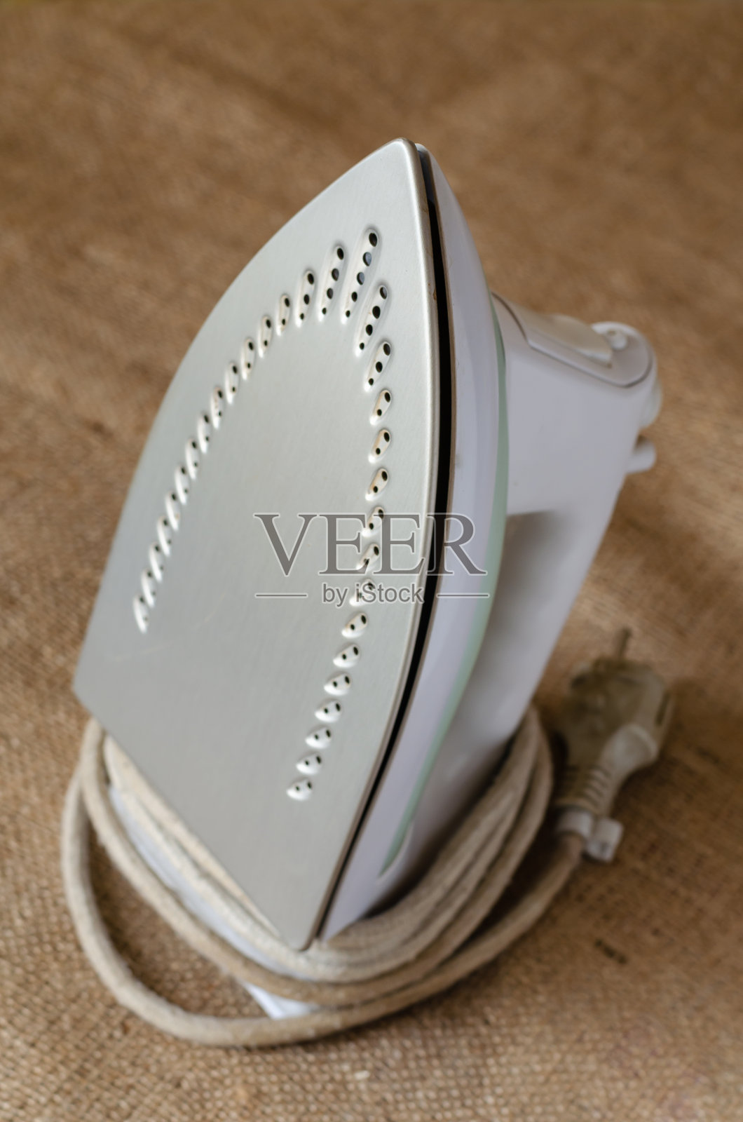 一个电熨斗放在粗麻布上。照片摄影图片