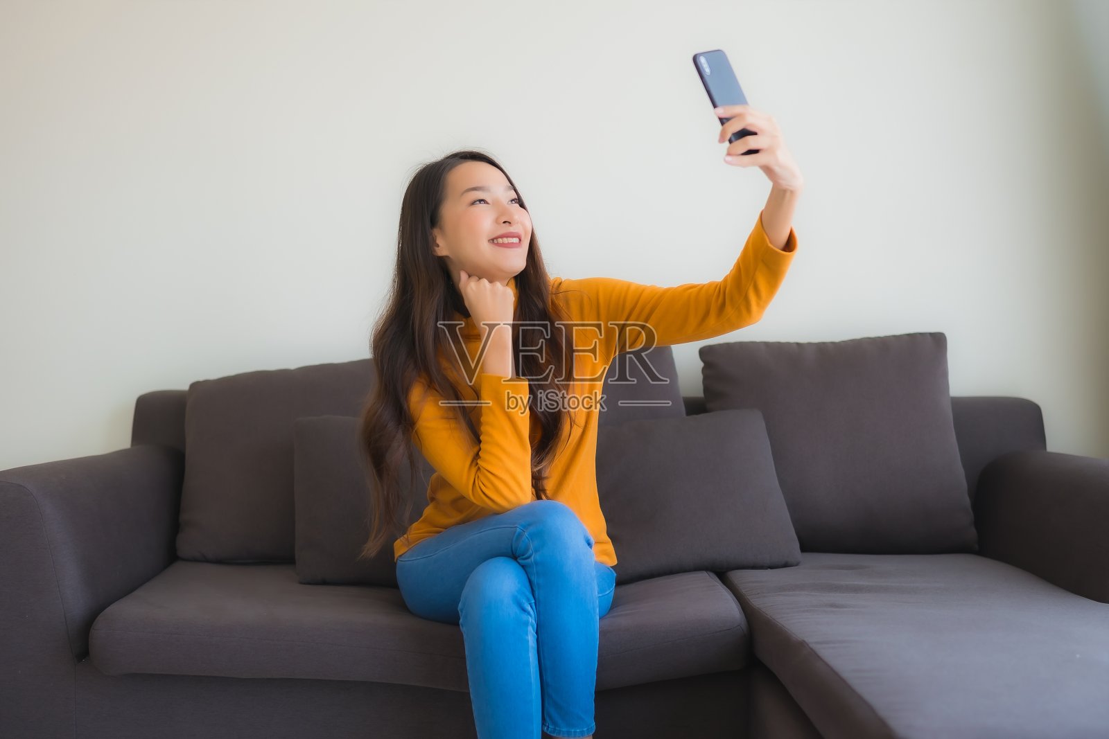 年轻亚洲女性在客厅沙发上用手机照片摄影图片