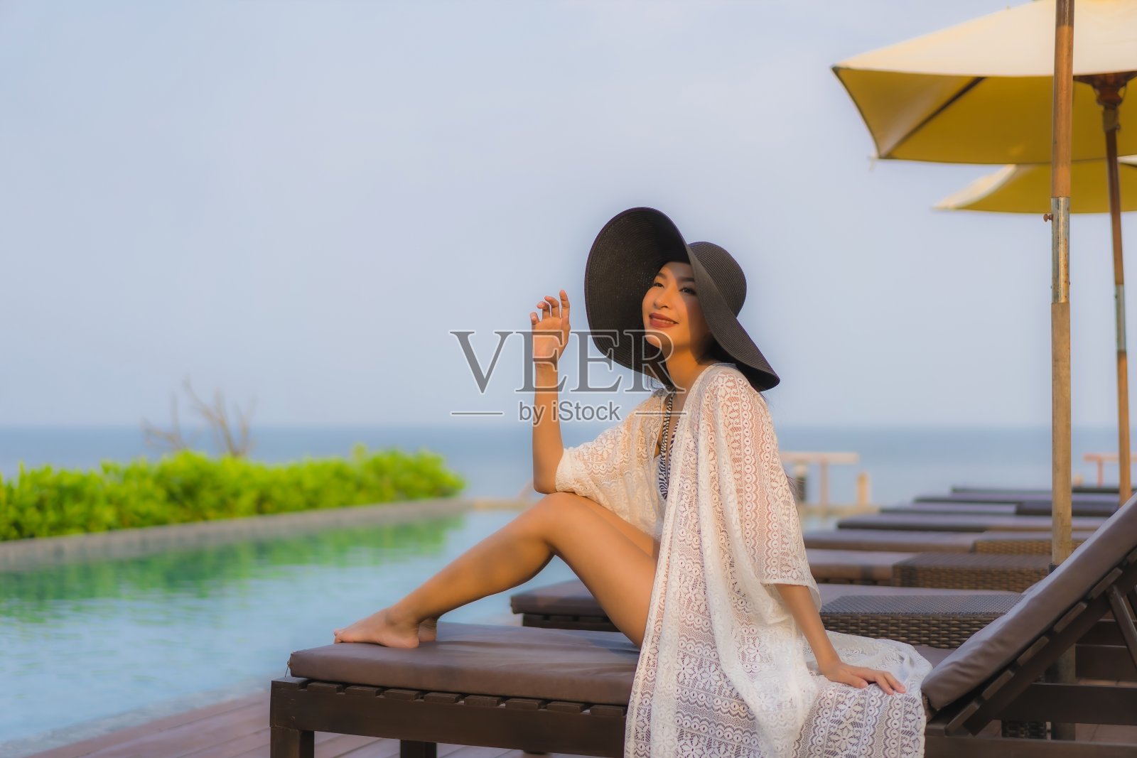 年轻亚洲女性在户外游泳池边放松微笑照片摄影图片