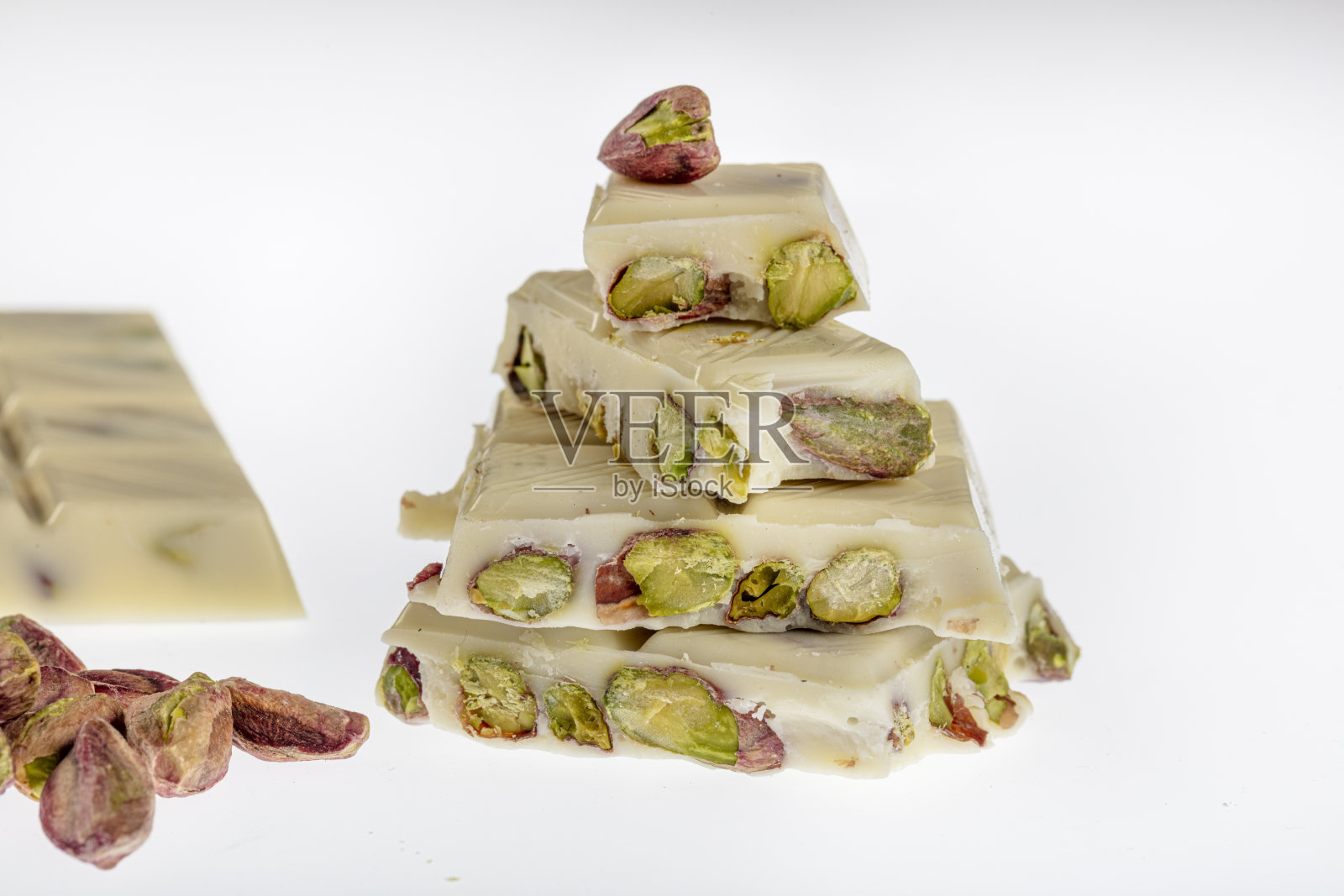 桌上放着白巧克力和巧克力塔。巧克力和开心果。照片摄影图片