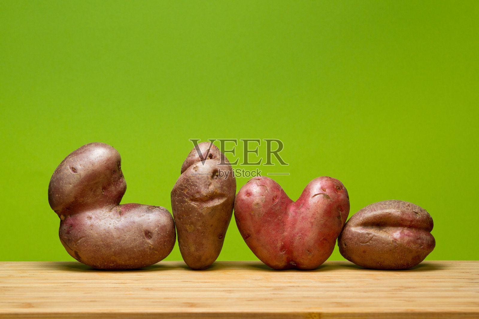 绿色背景下丑陋的蔬菜。这对素食者来说是个有趣的概念。波普艺术。LIVE这个词是由变形的土豆组成的。水平方向。本空间照片摄影图片