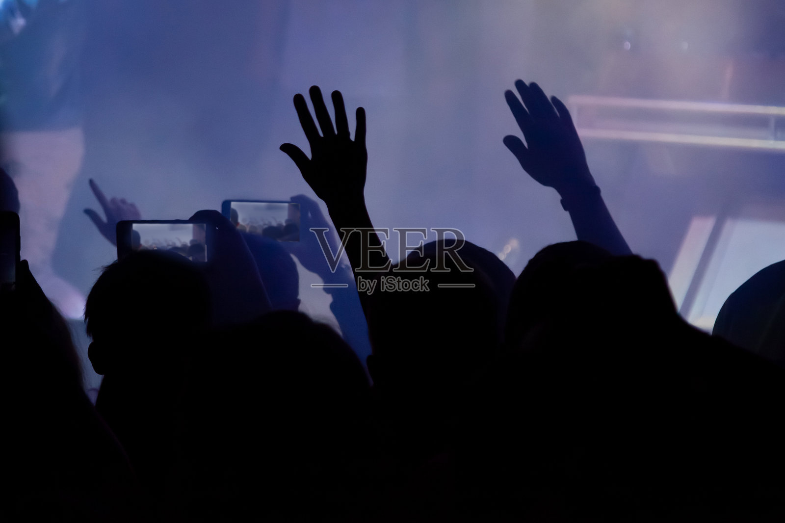 手持智能手机录制现场音乐节,拍摄音乐会舞台照片。在夜总会的聚会上,一群人举起手拿着手机。照片摄影图片