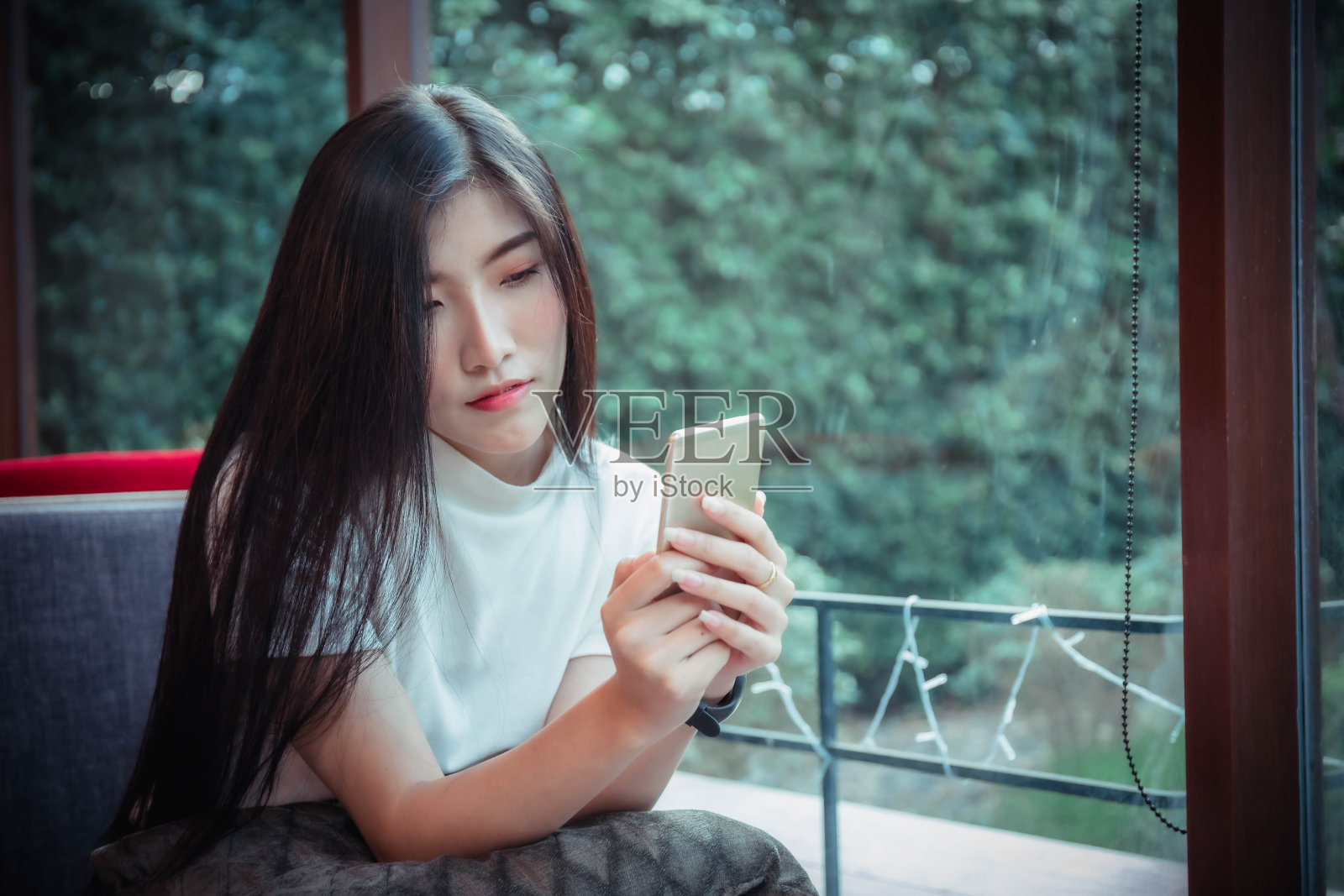 美丽的亚洲女孩拿着手机,快乐地看着手机照片摄影图片