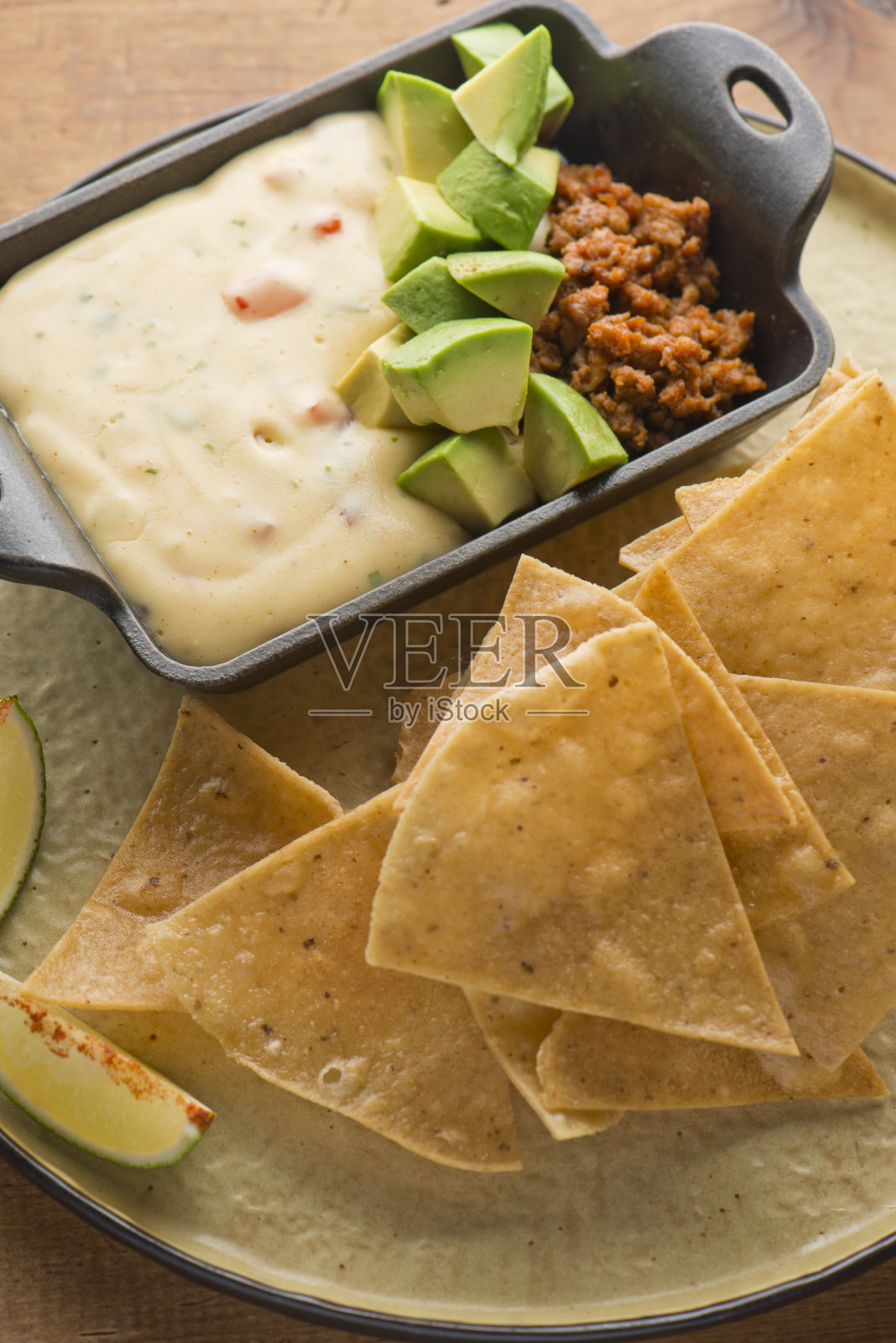 Queso奶酪倾斜。传统经典的德州-墨西哥/墨西哥餐厅开胃菜最爱。芝士蘸酱融化的芝士与香料和辣酱混合。配自制玉米片、牛油果和肉照片摄影图片