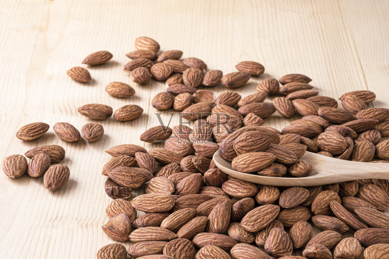 近景杏仁从木勺倒在麻袋和桌子上。照片摄影图片