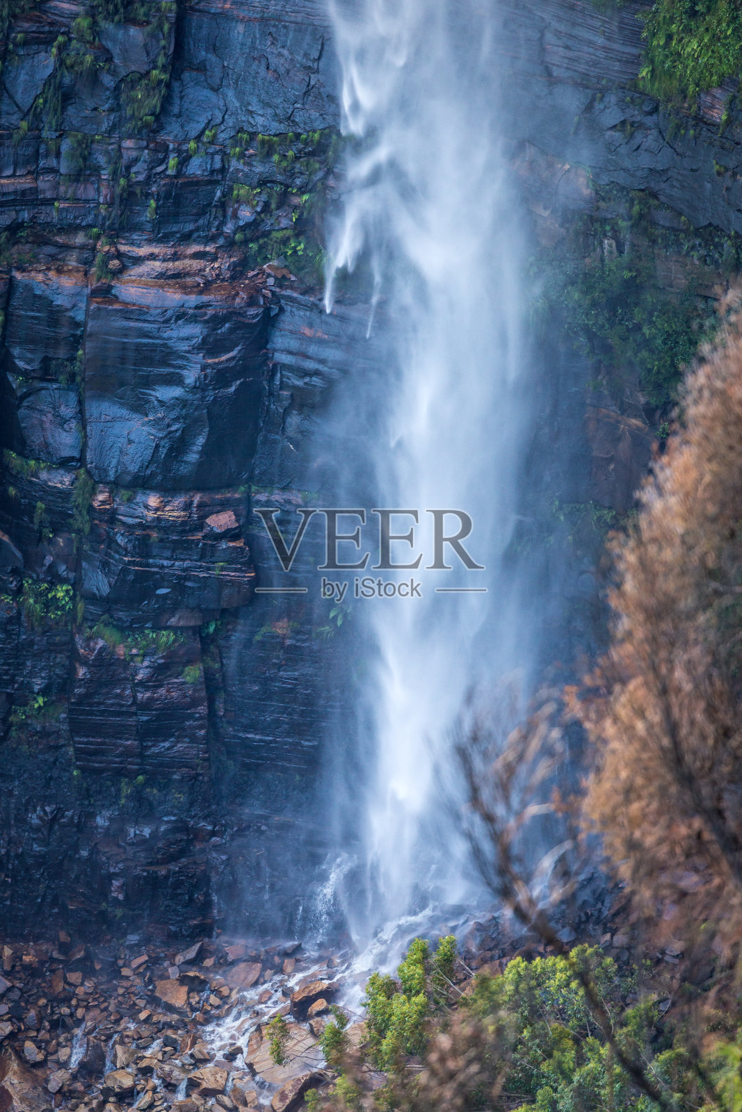 瀑布从悬崖上一泻而下,直泻到巨石上照片摄影图片