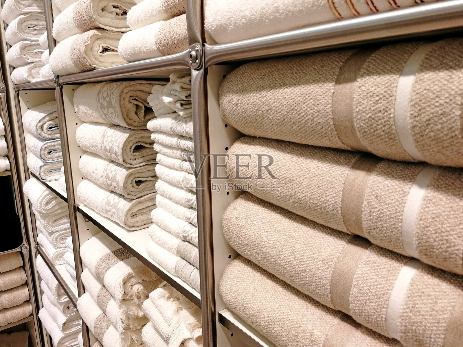 在商店里,不同种类的毯子和床罩排成一排摆放在货架上。室内纺织品购物的概念照片摄影图片