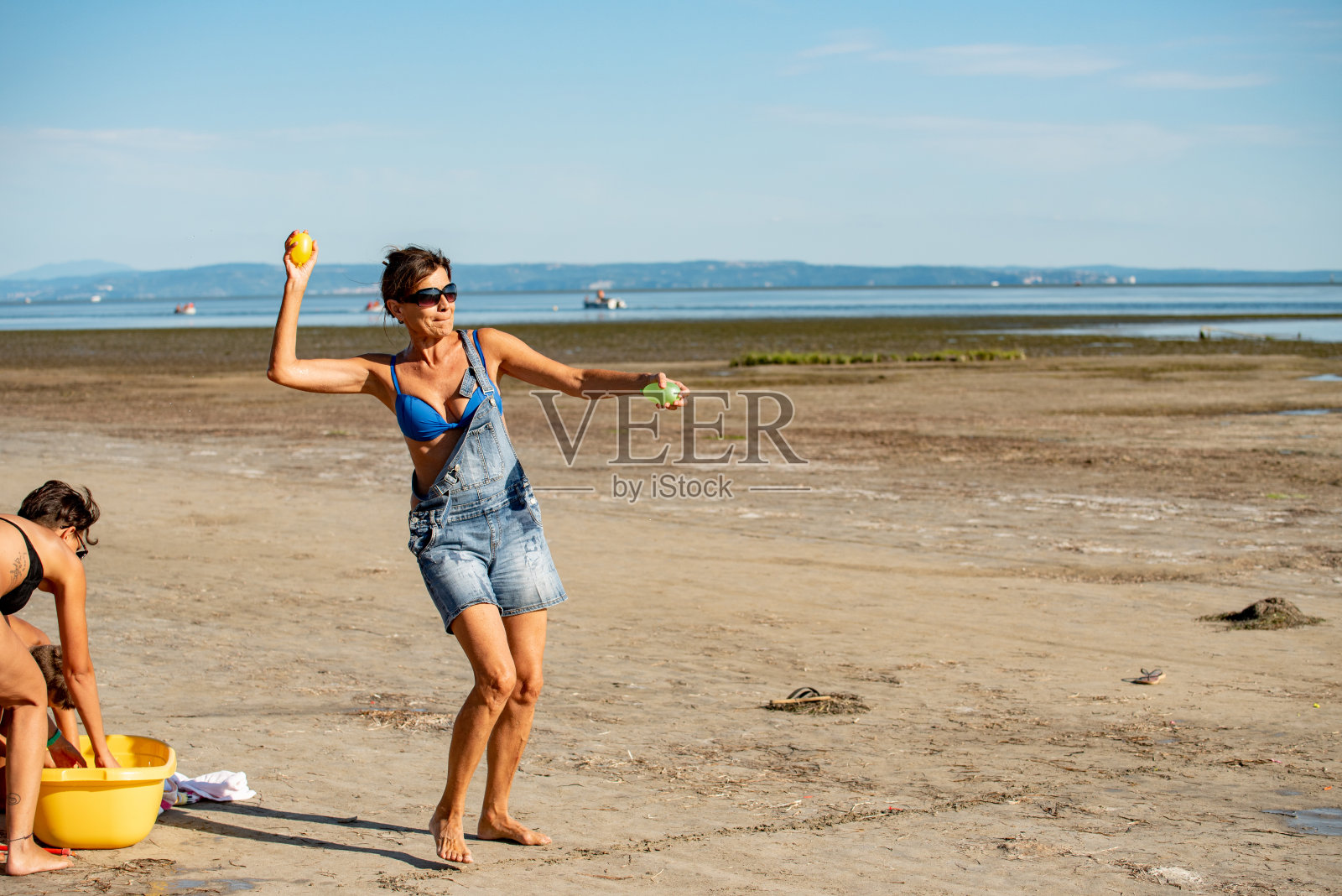 阳光明媚的海滩上,中年妇女们在扔水弹 - 摄影素材照片摄影图片