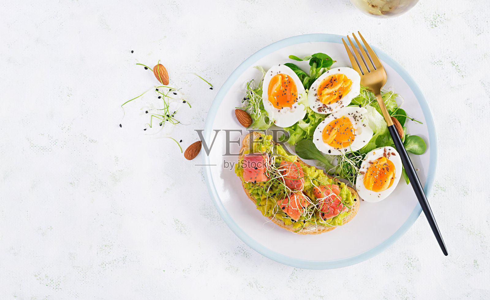 早餐。健康开放三明治吐司与鳄梨和鲑鱼,煮鸡蛋,香草,奇亚籽在白色盘子复制空间。健康的蛋白质食物。顶视图,开销照片摄影图片