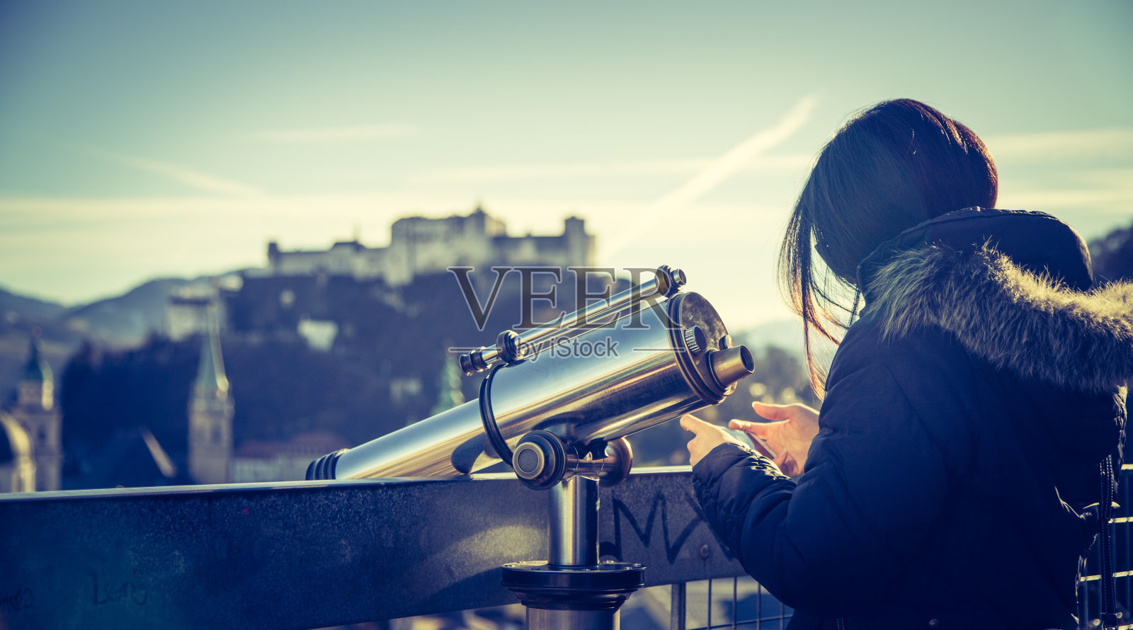 参观萨尔茨堡:年轻女孩在僧侣山上使用观光望远镜,背景是模糊的要塞照片摄影图片
