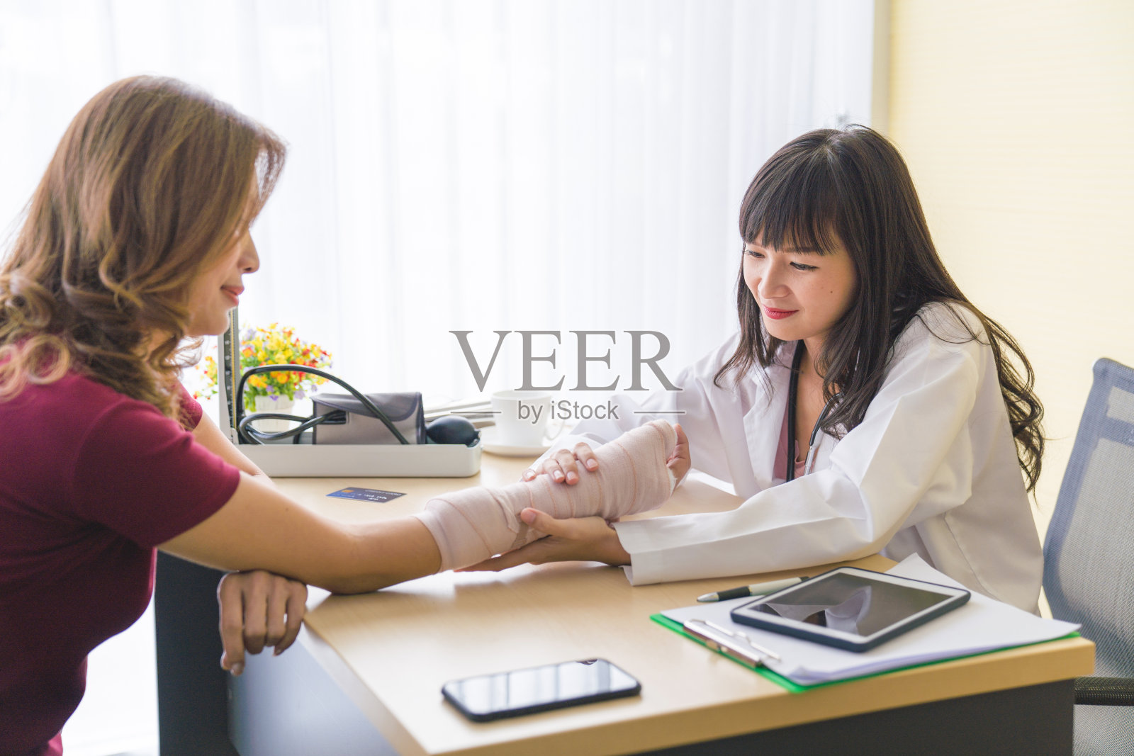 专业医生向坐在轮椅上的女性解释X光片,女性手臂骨折并用绷带包扎照片摄影图片