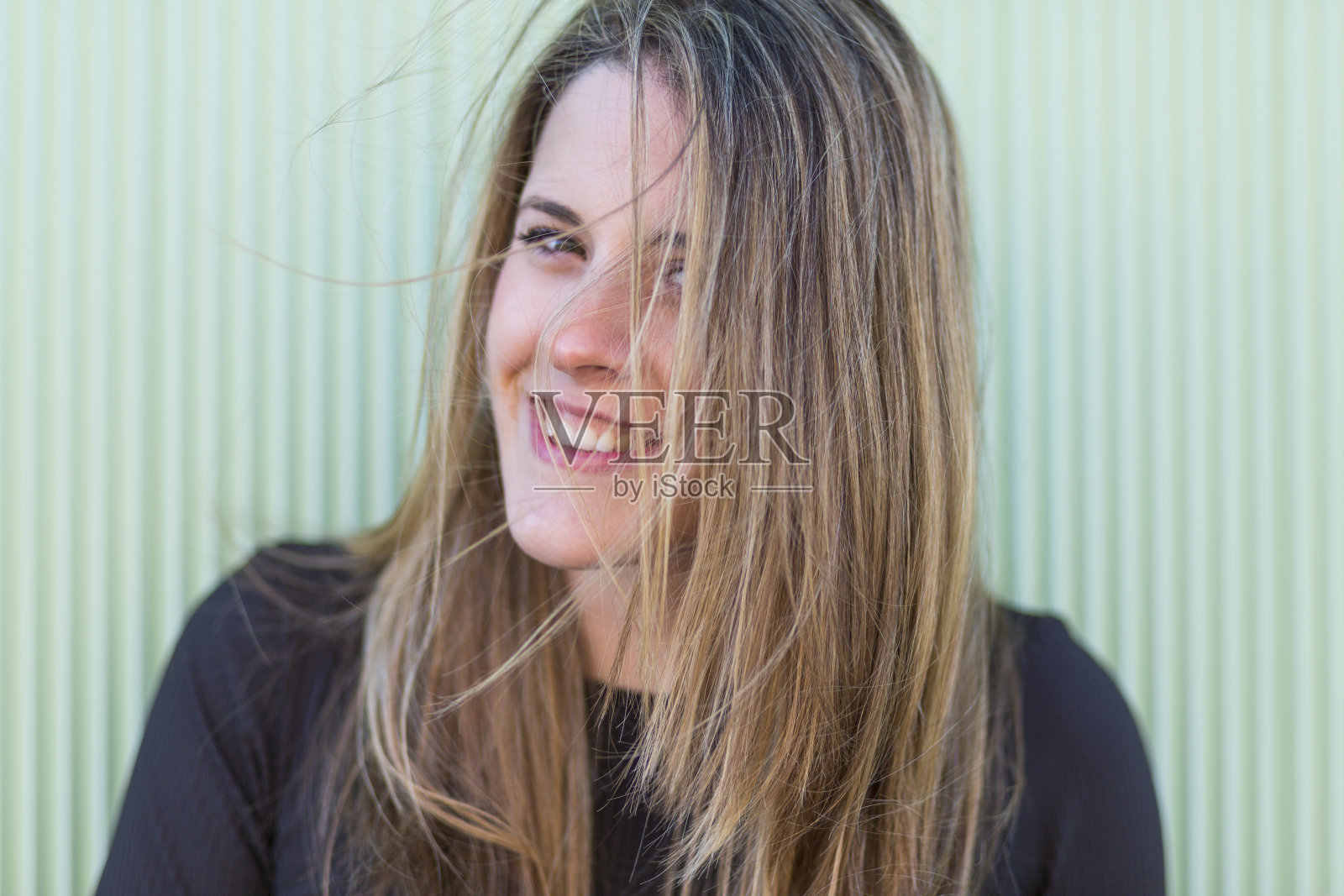 一个美丽的年轻女子的近距离肖像在绿色的背景微笑。积极情绪照片摄影图片